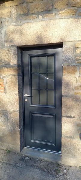Porte bleu avec vitre quadrillée et encadrure en pierre