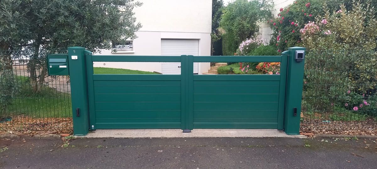 Portail vert devant maison avec jardin