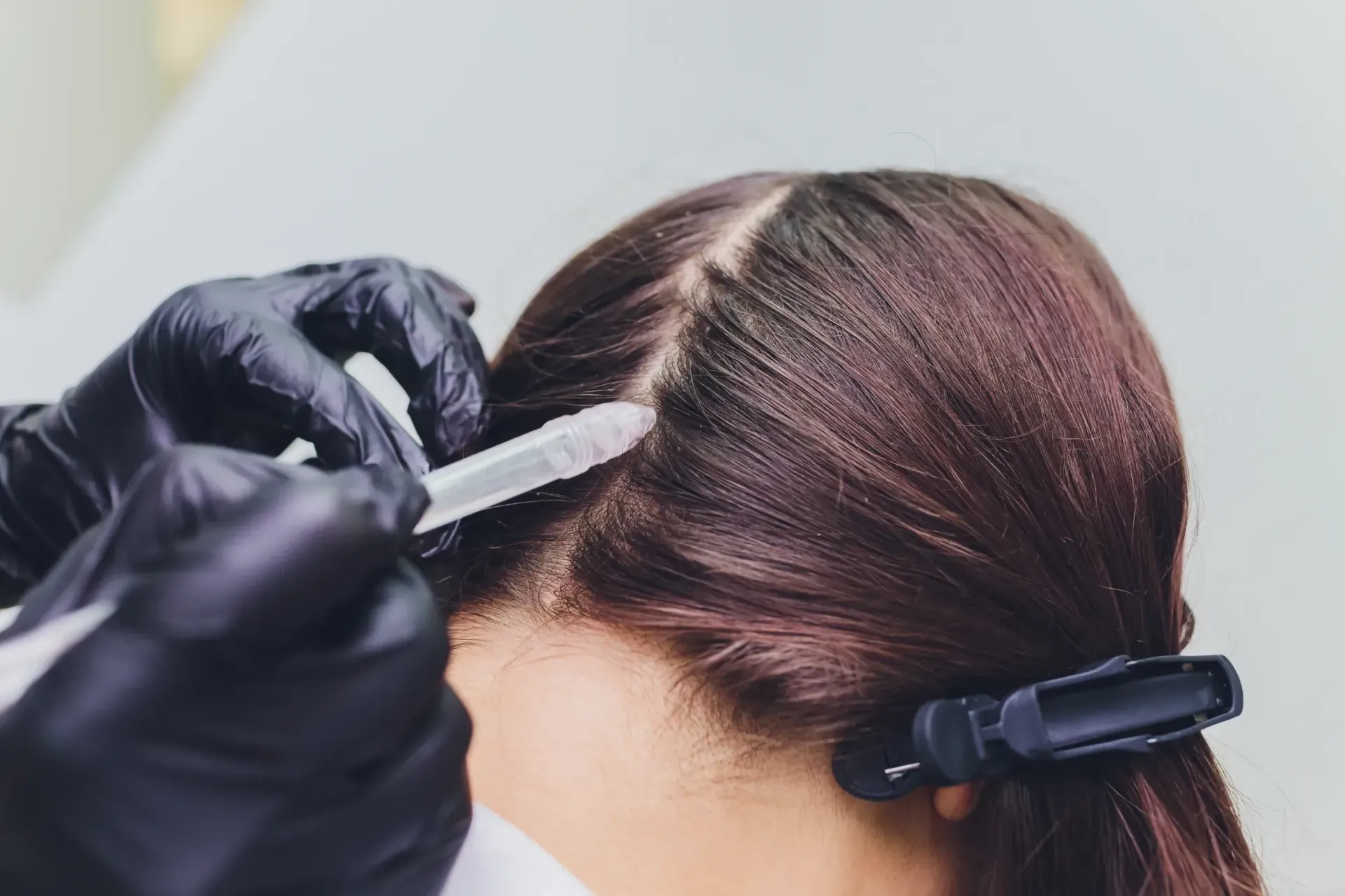 Una mujer se está tiñendo el pelo en la peluquería.
