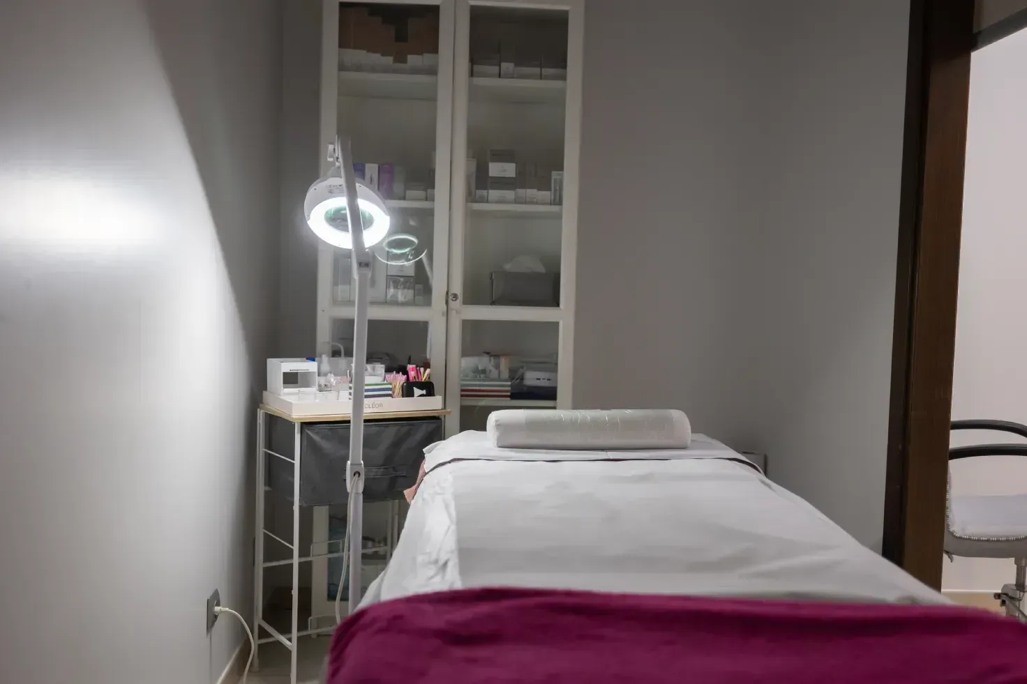 Una mesa de masajes en una habitación con una manta morada y una lámpara.