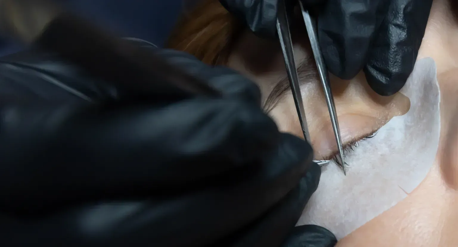 Una mujer se está haciendo las cejas con una persona que lleva guantes negros.