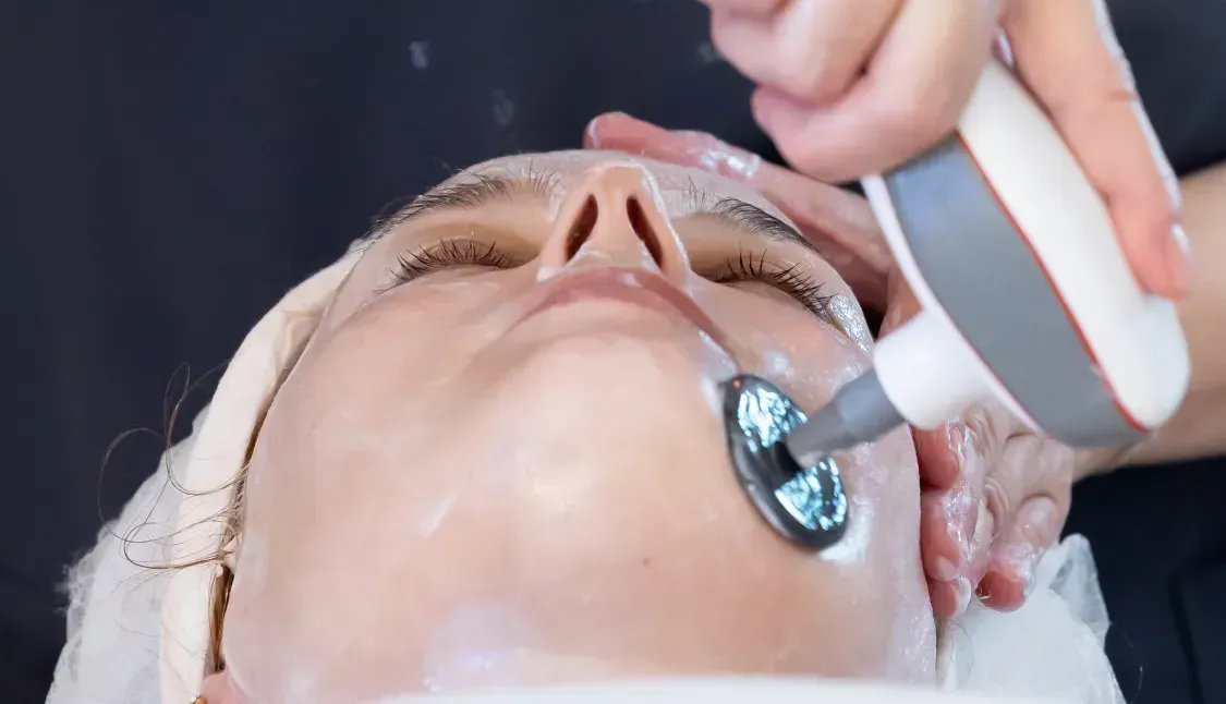 Una mujer está recibiendo un tratamiento facial con una máquina en su cara.