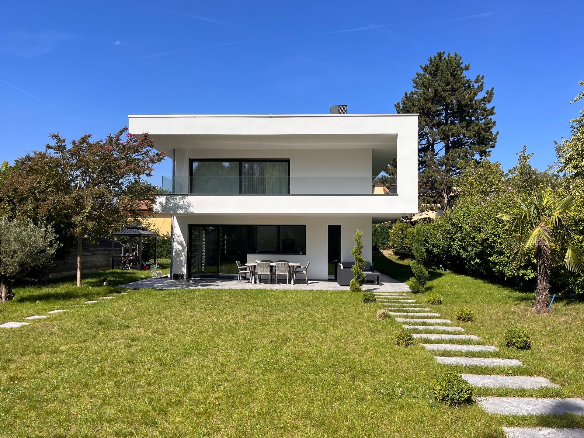 A modern white house with a large lawn in front of it.