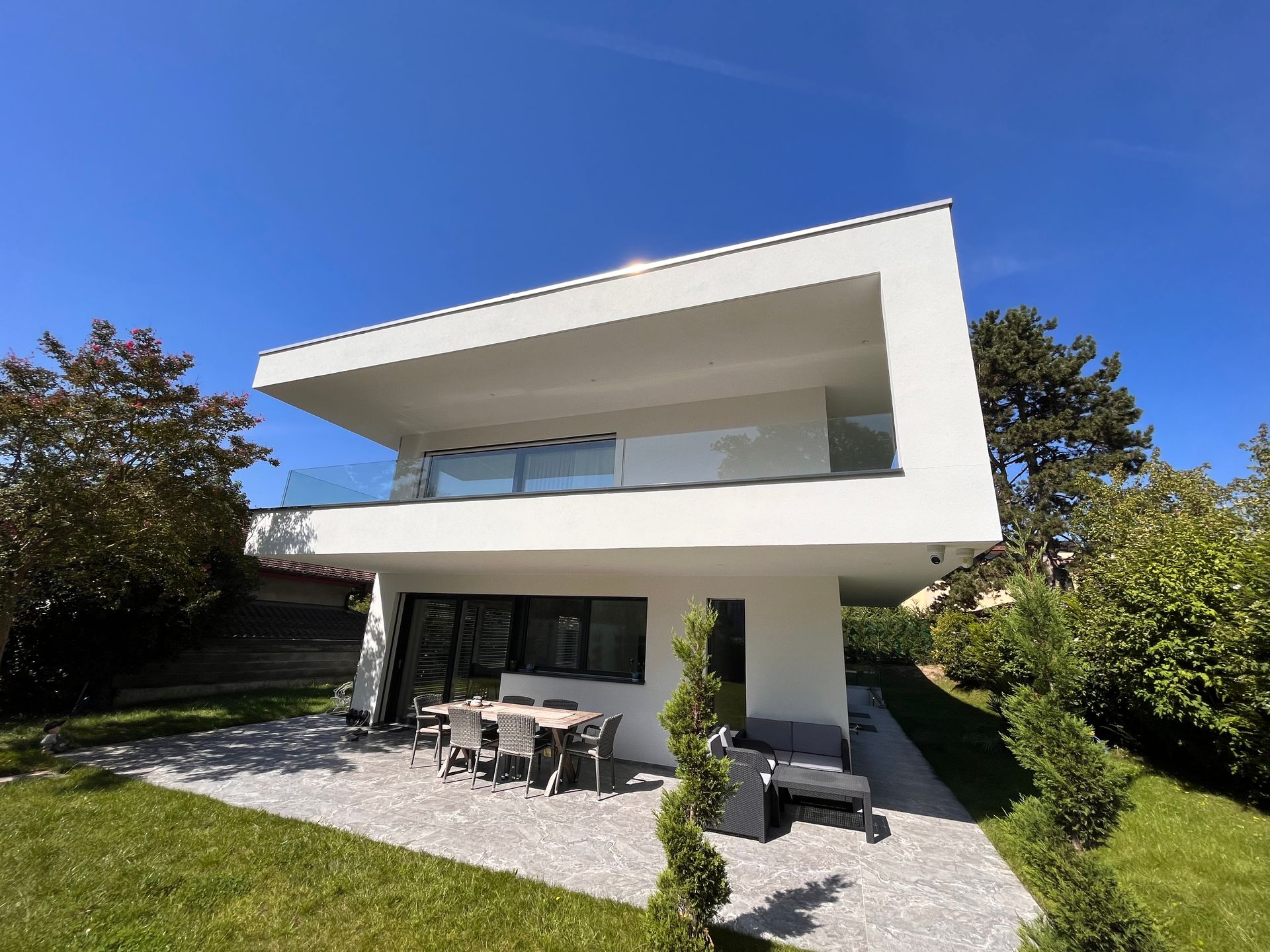 A white house with a patio and a table and chairs in front of it.