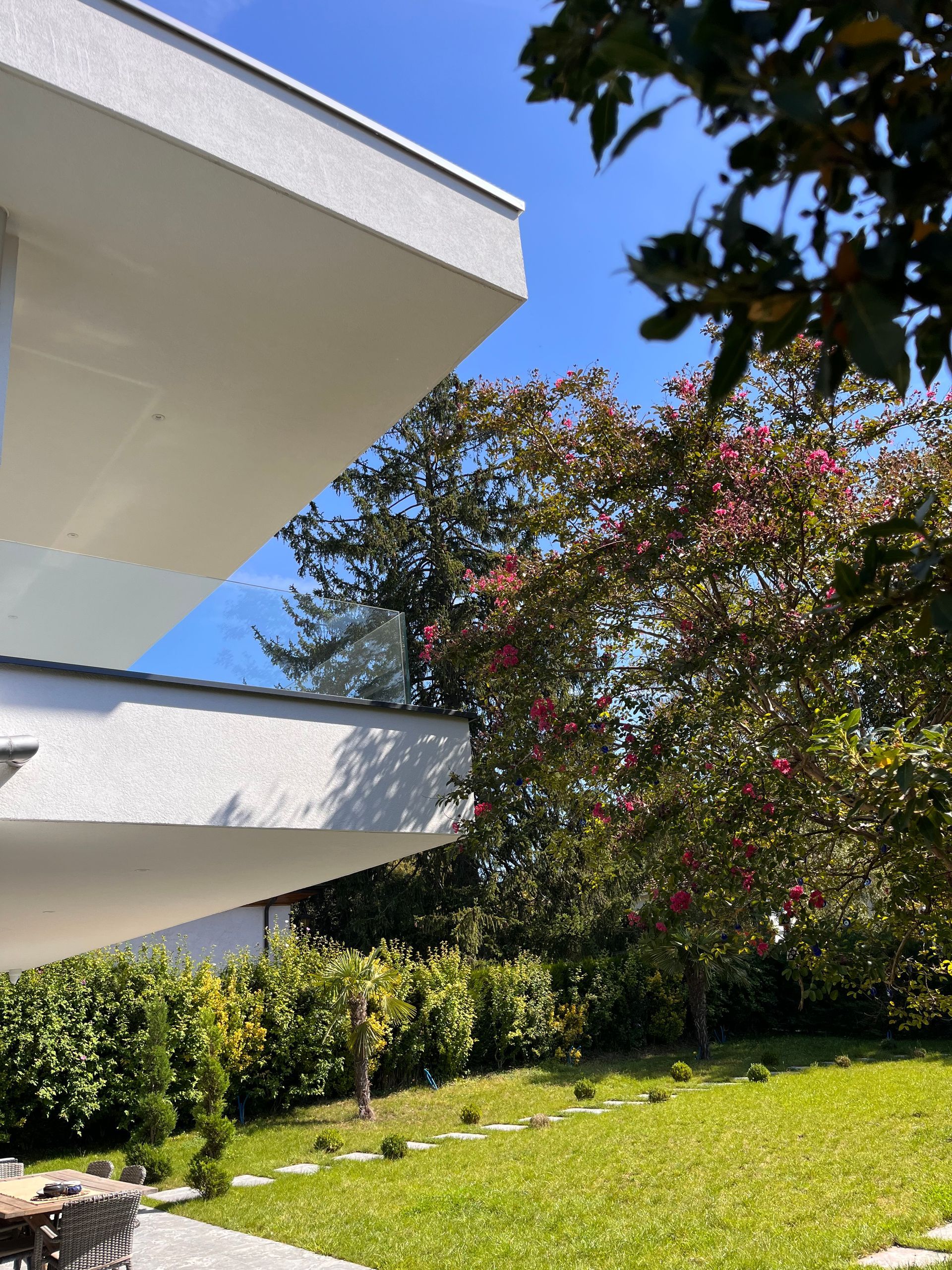 A house with a balcony and a lawn in front of it