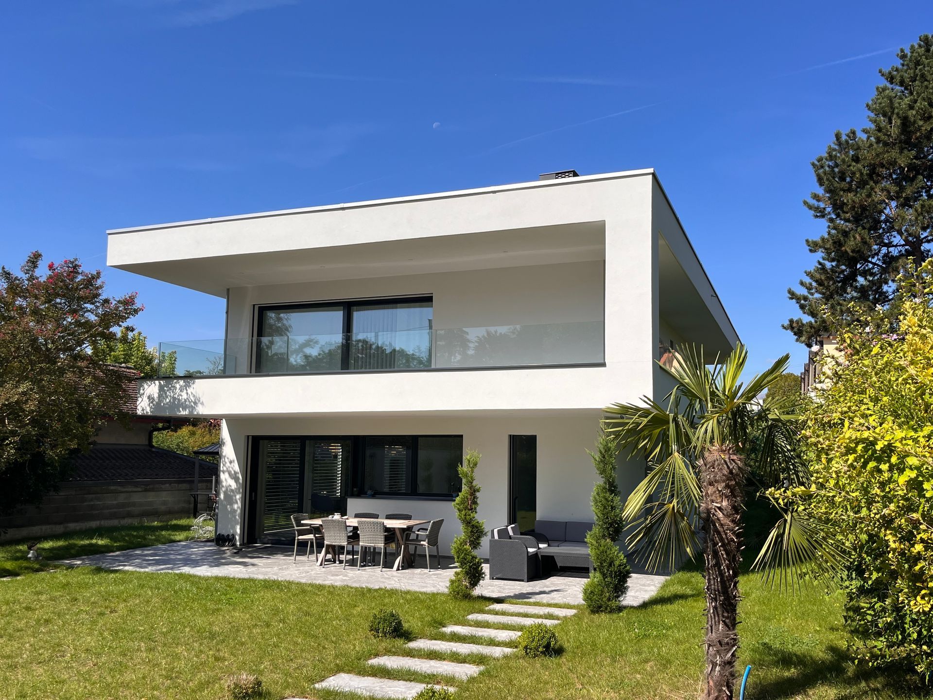 A large white house with a lot of windows is sitting on top of a lush green lawn.
