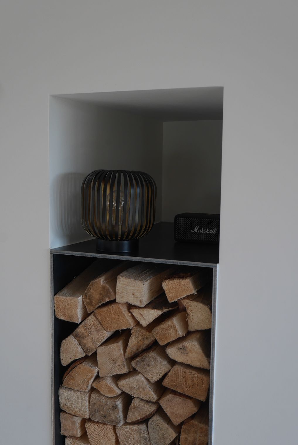 A pile of wood is sitting in a niche in a wall.