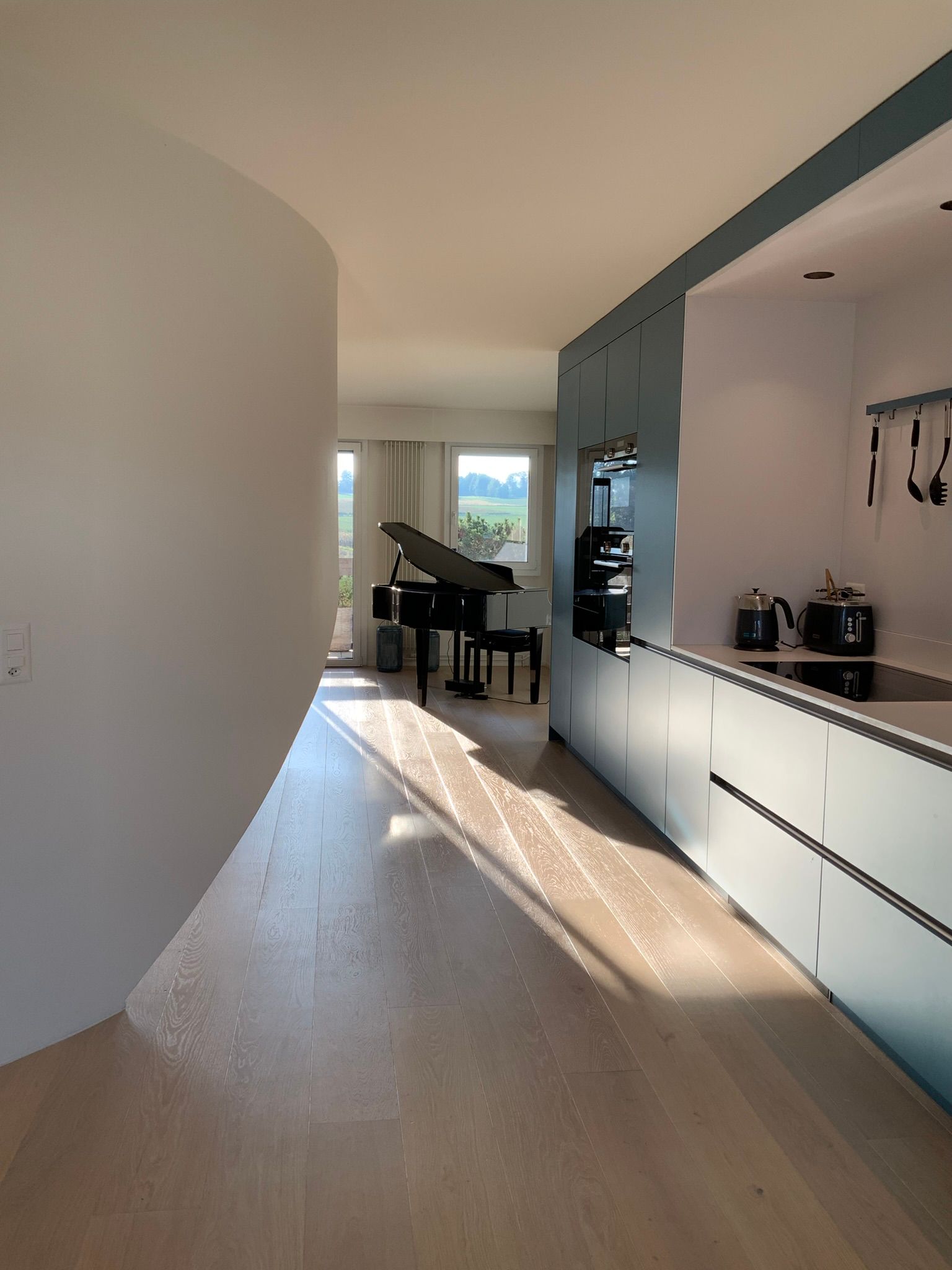 A living room with a piano and a kitchen