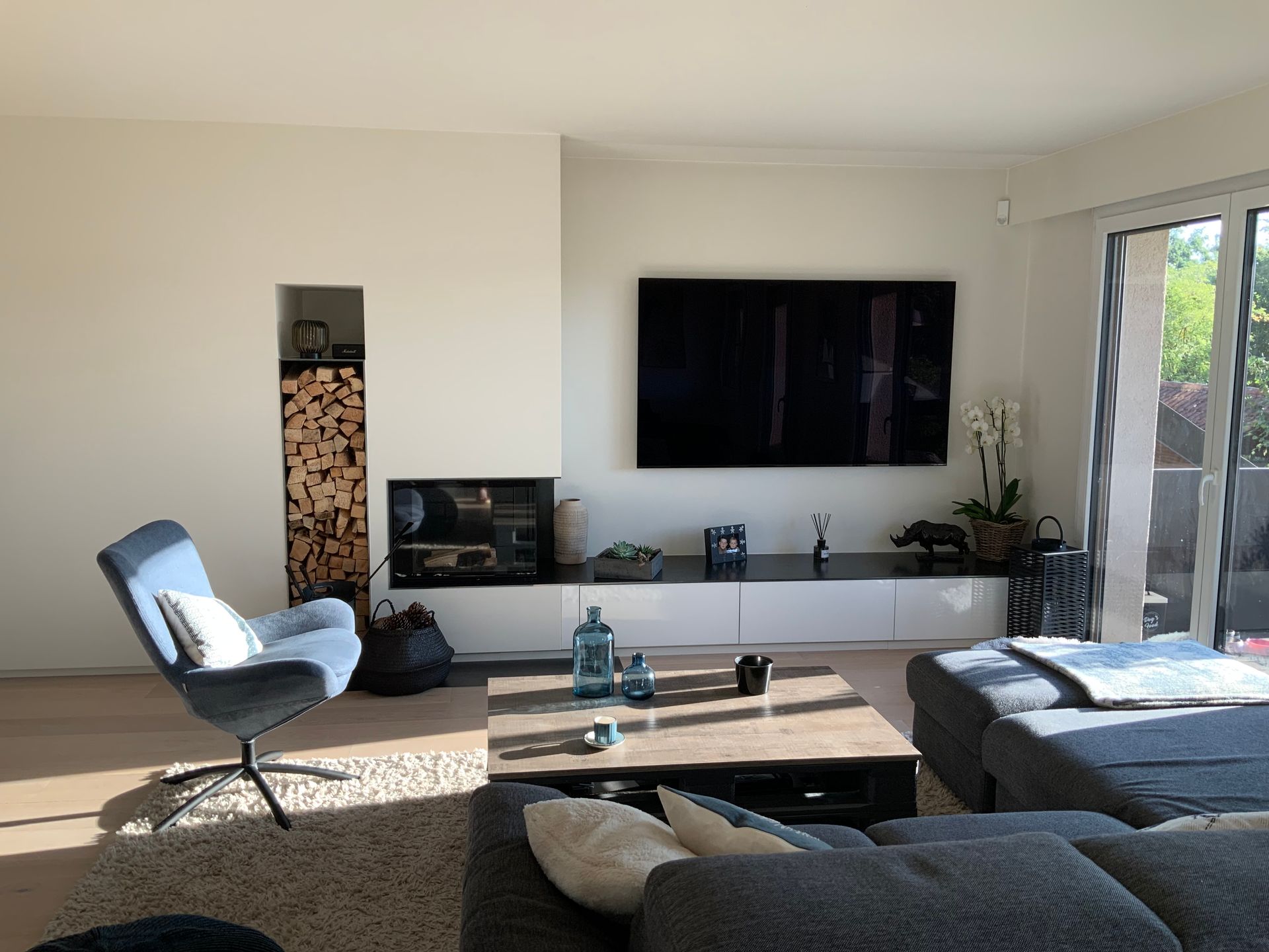A living room with a couch , chair , television and fireplace.