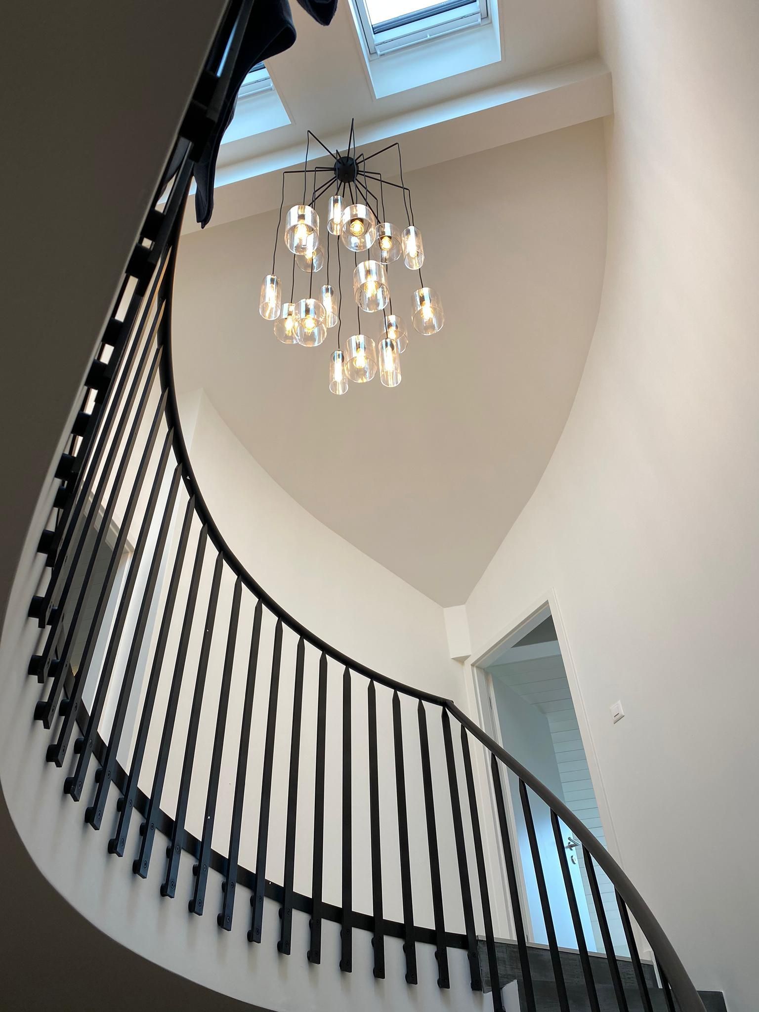 Looking up at a spiral staircase with a chandelier hanging from the ceiling