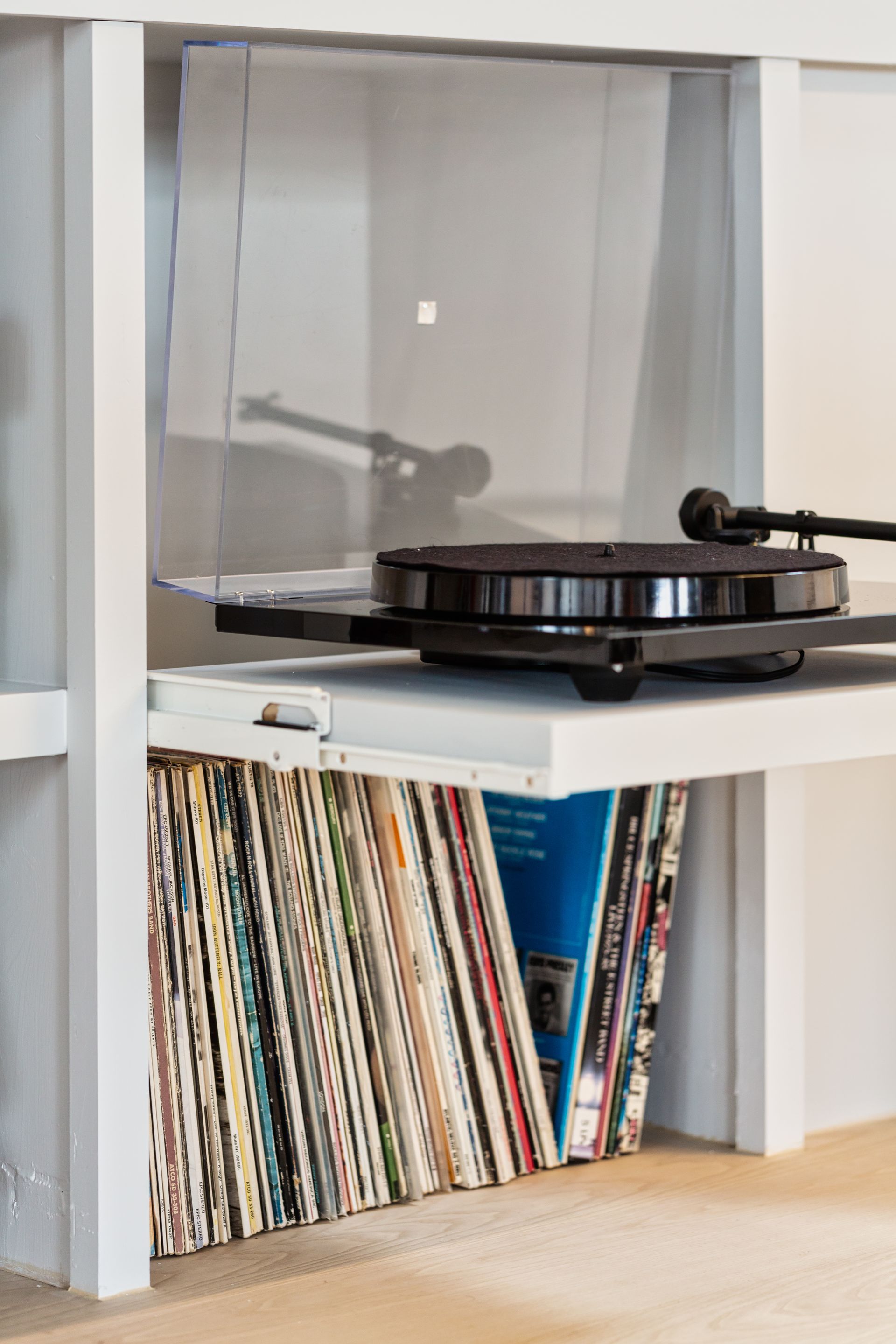 A record player is sitting on top of a shelf filled with records.