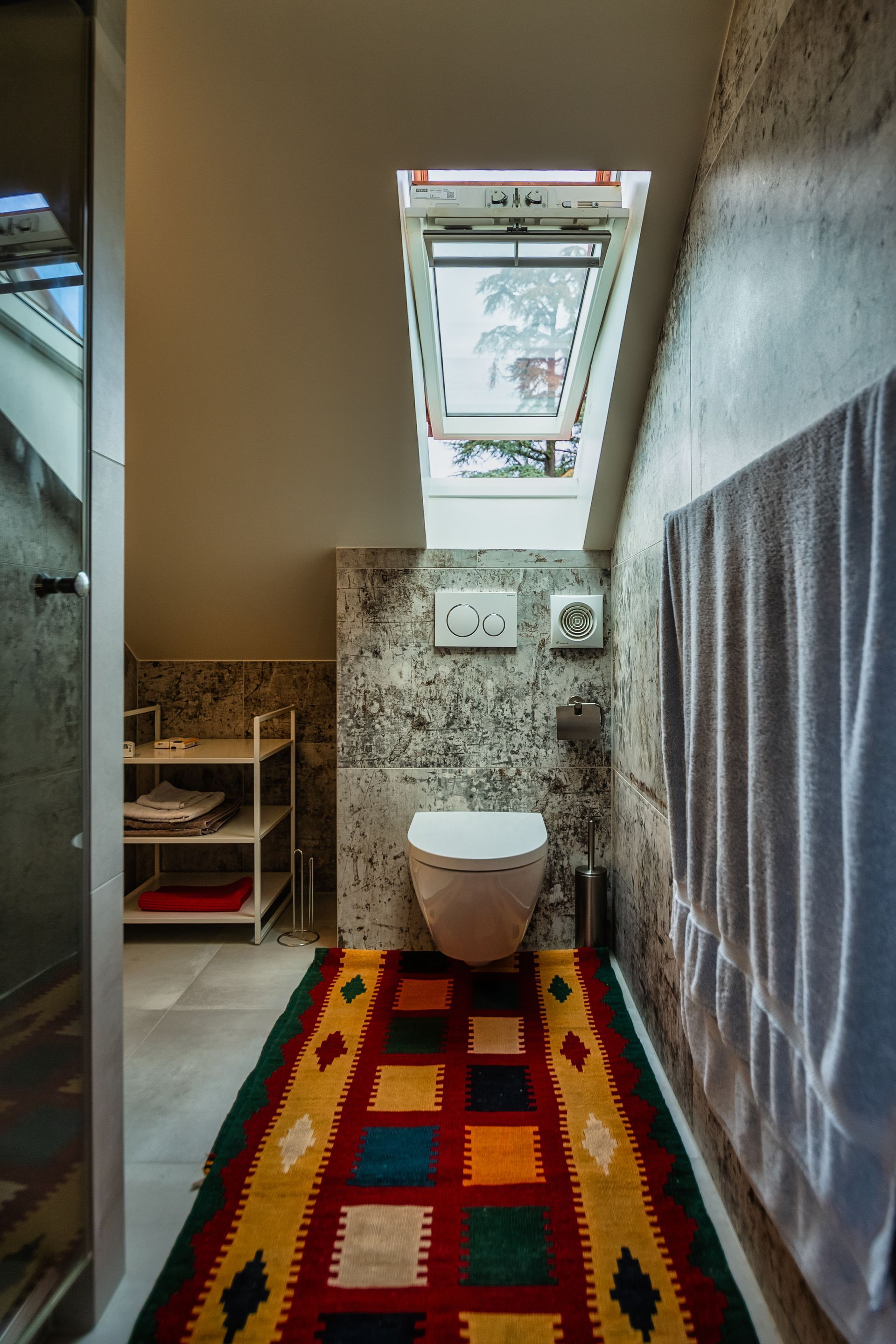 A bathroom with a toilet , rug and skylight.