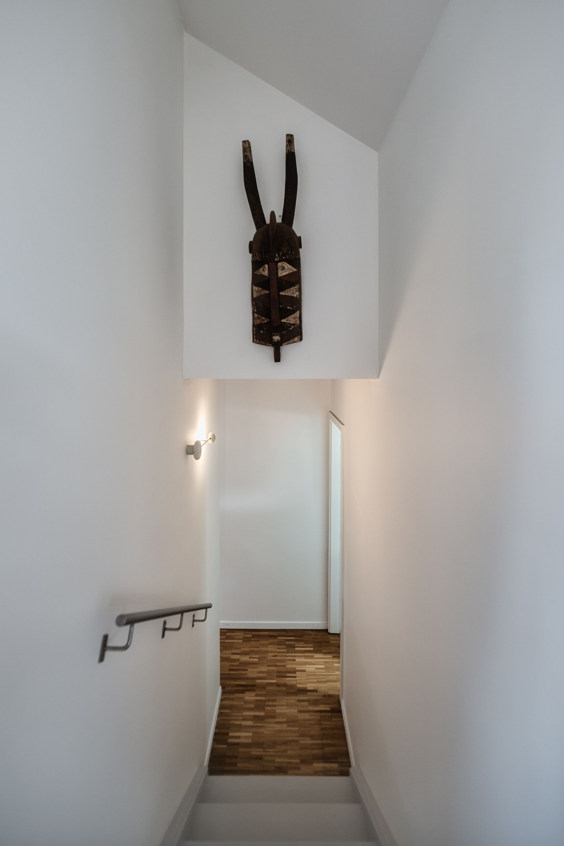 A staircase leading up to a second floor with a sculpture on the wall.