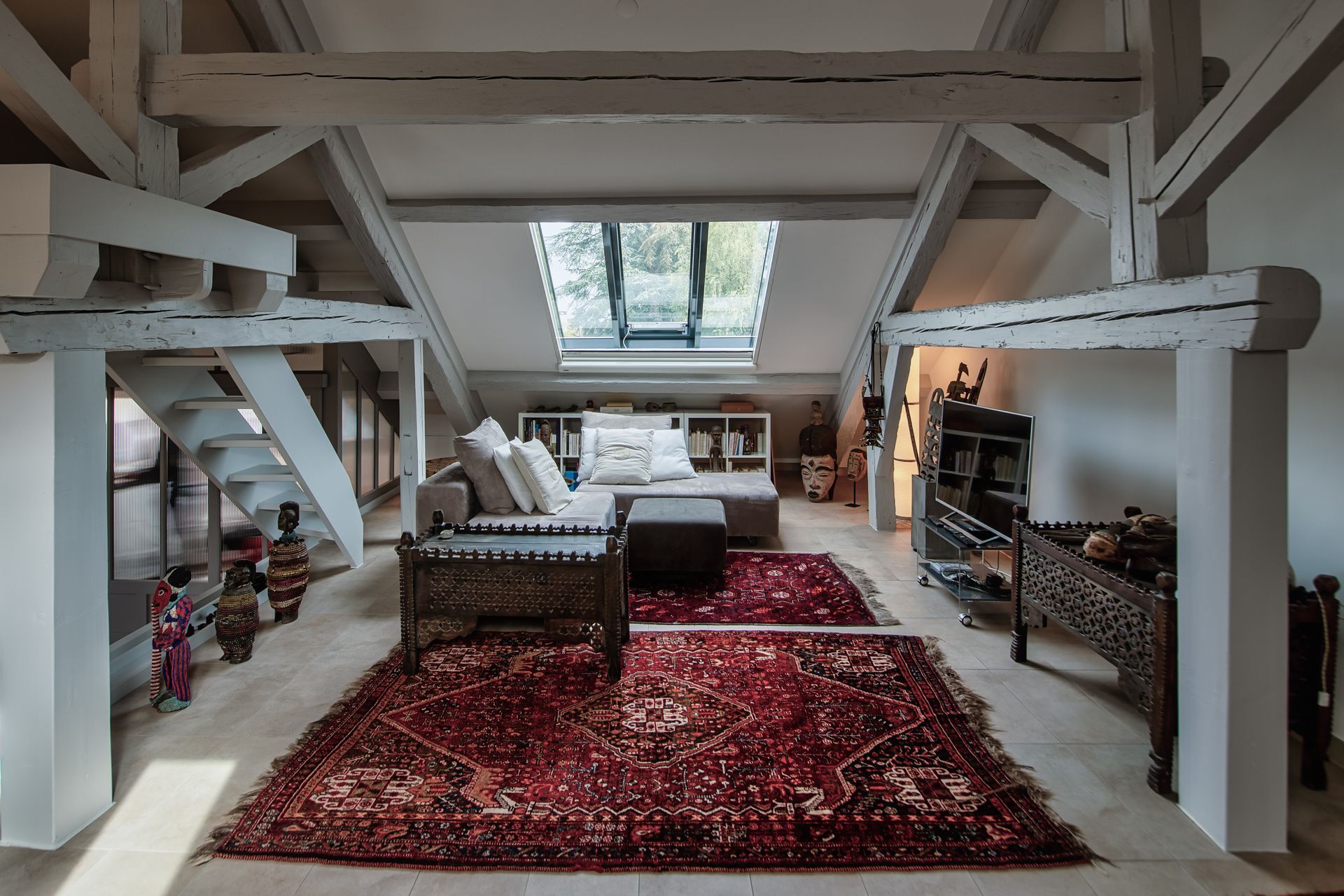 A living room with a couch , rug and a skylight in the ceiling.