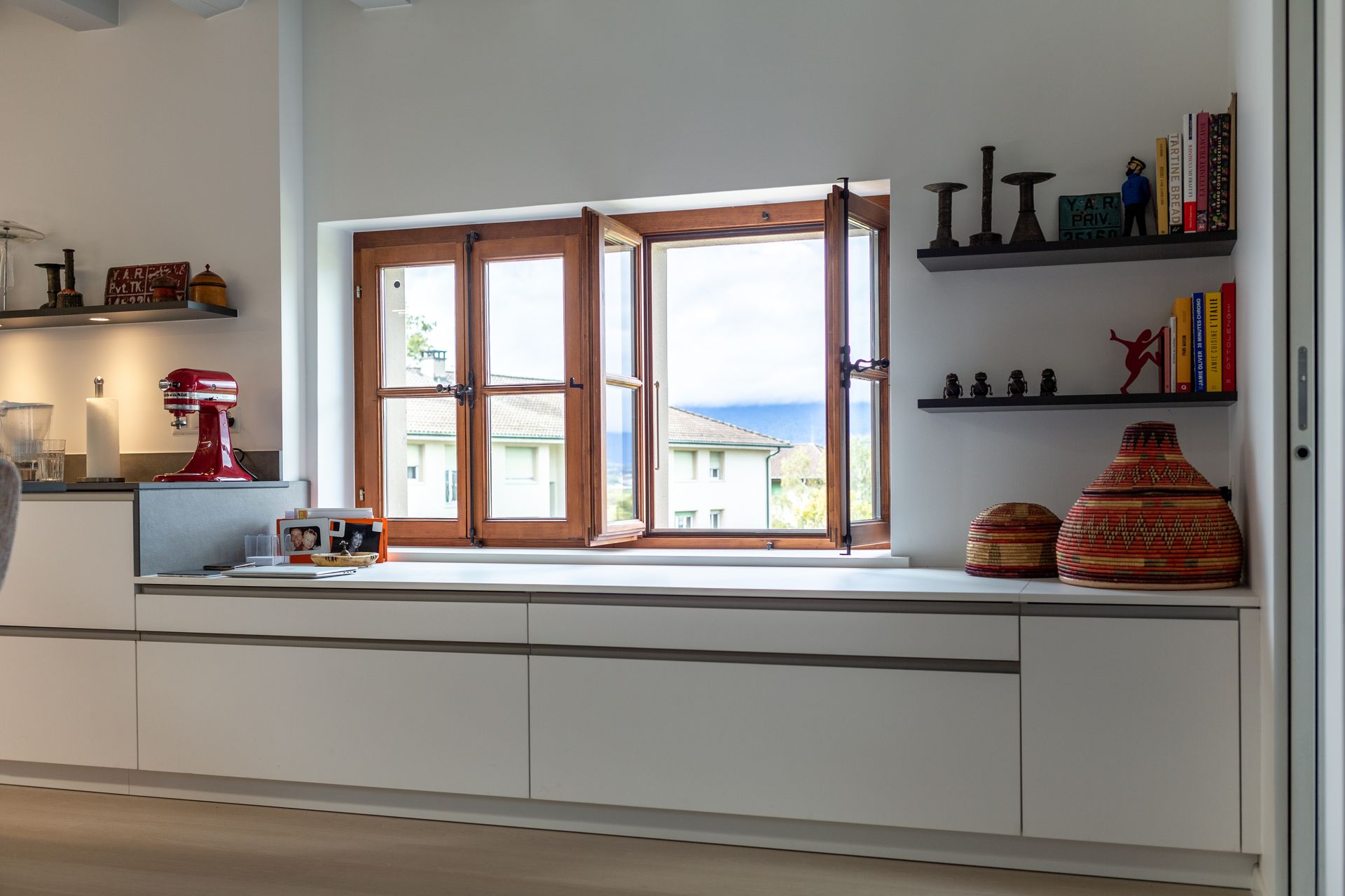 A kitchen with white cabinets and a window with a view of the ocean.
