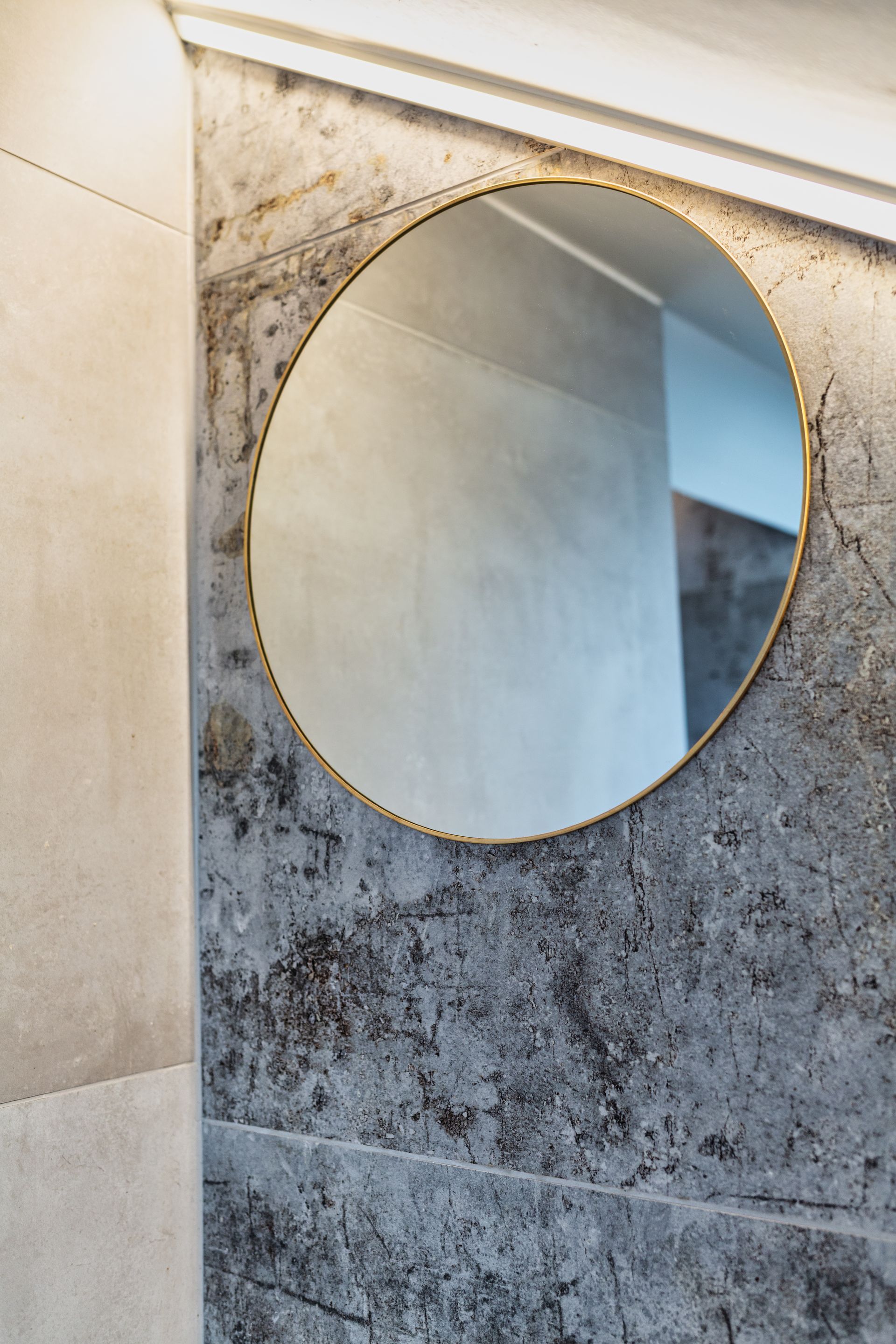 A round mirror is hanging on a wall in a bathroom.