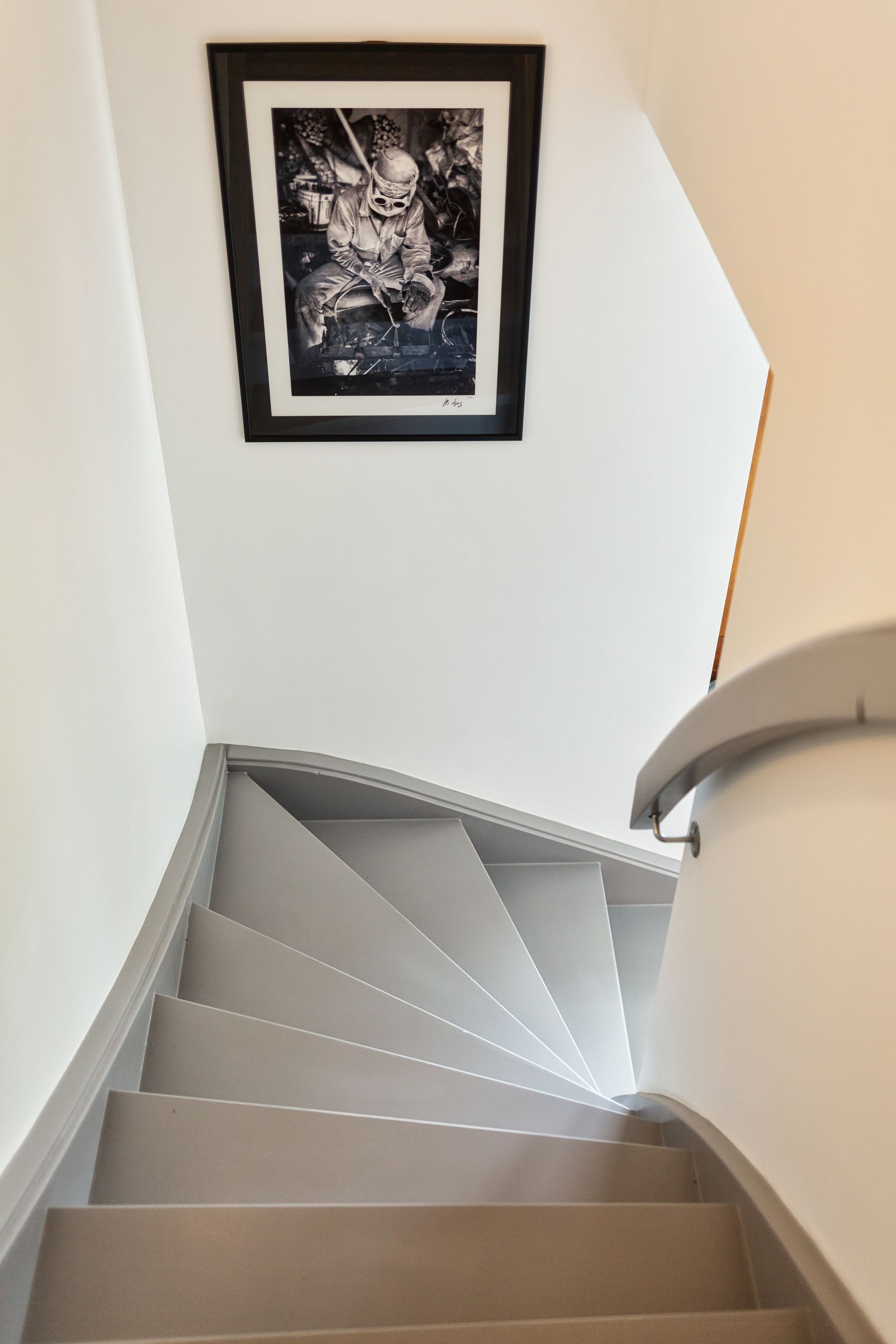 A staircase with a picture on the wall above it