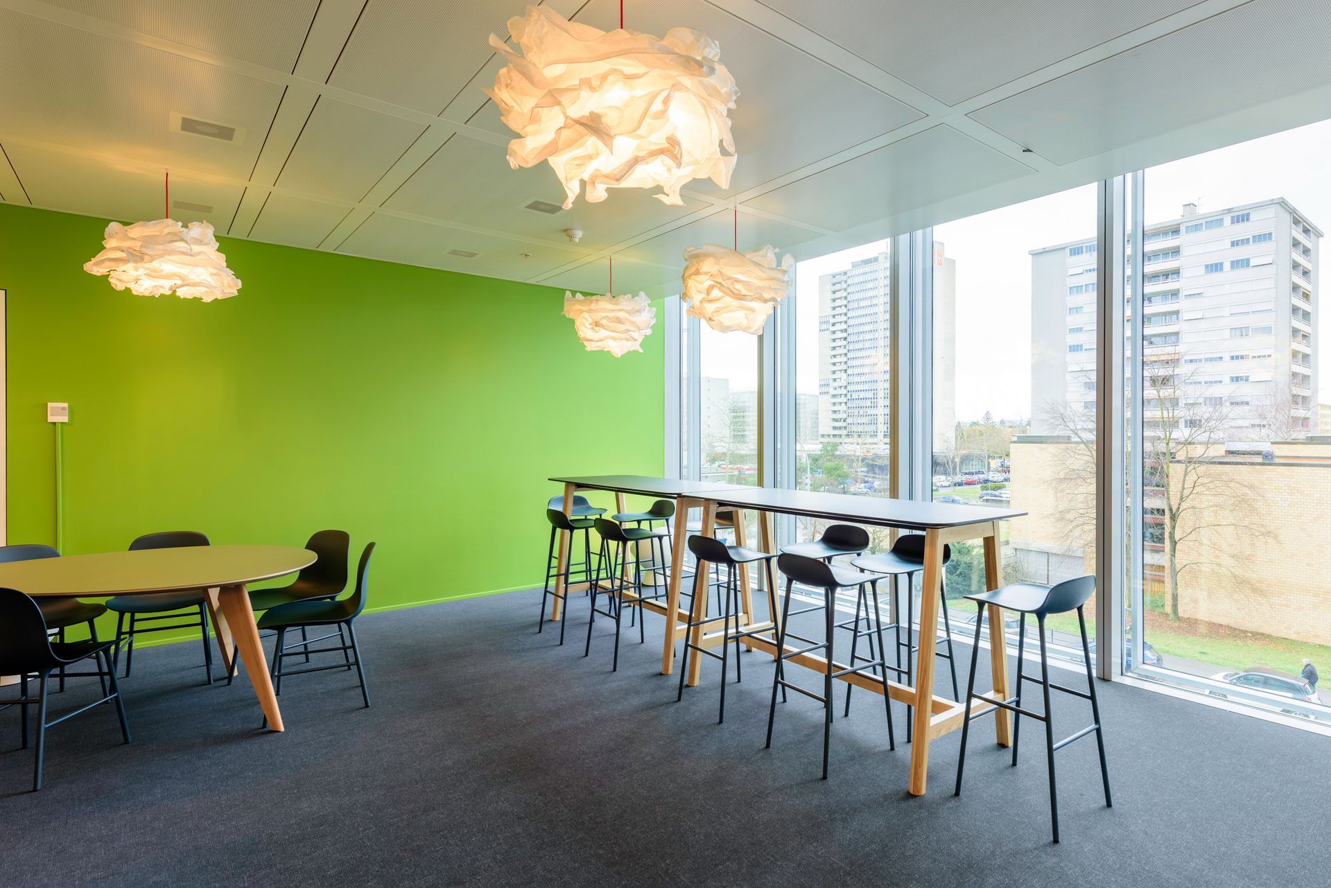 A room with tables and chairs and a green wall.