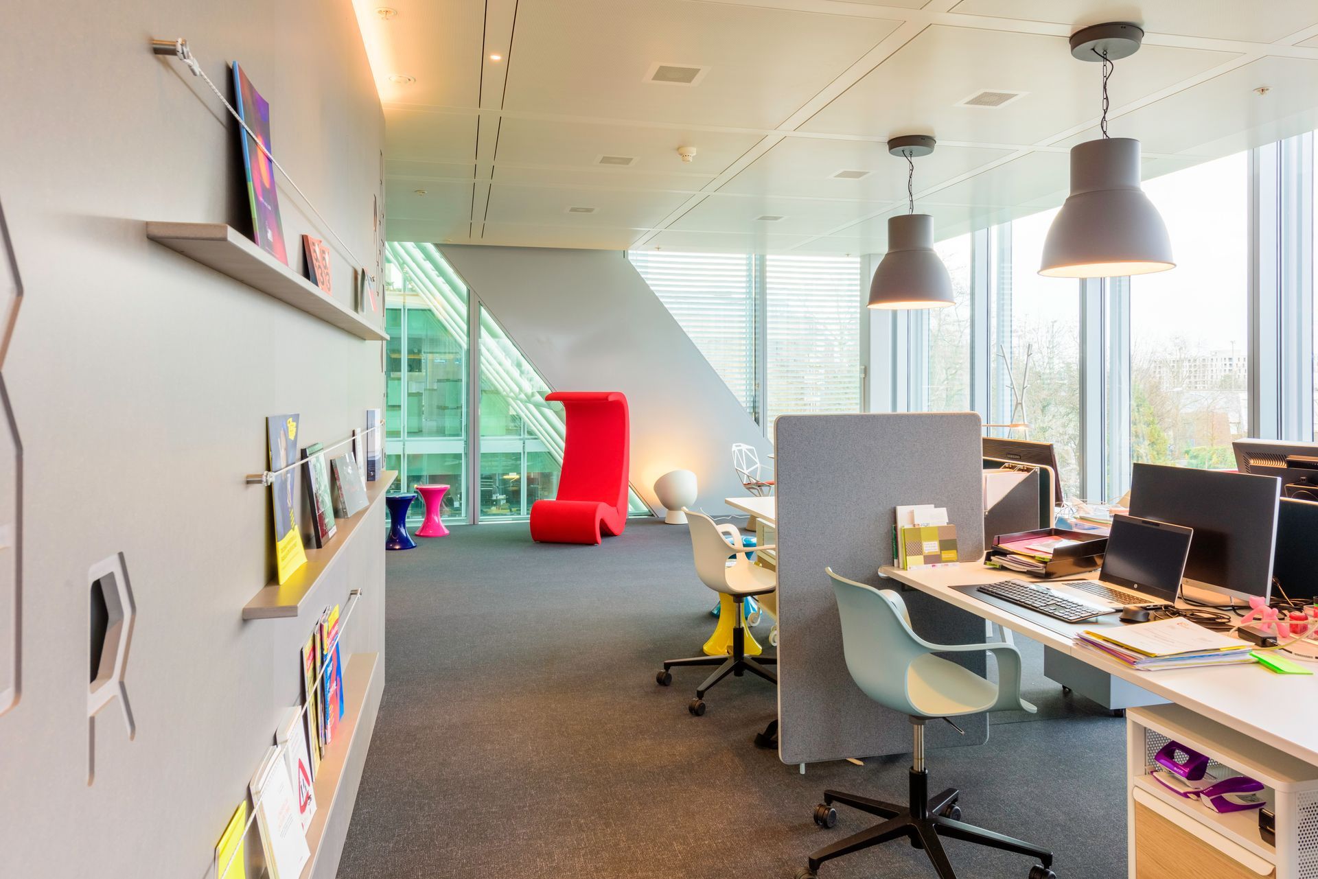 A large office with a lot of windows and desks and chairs.
