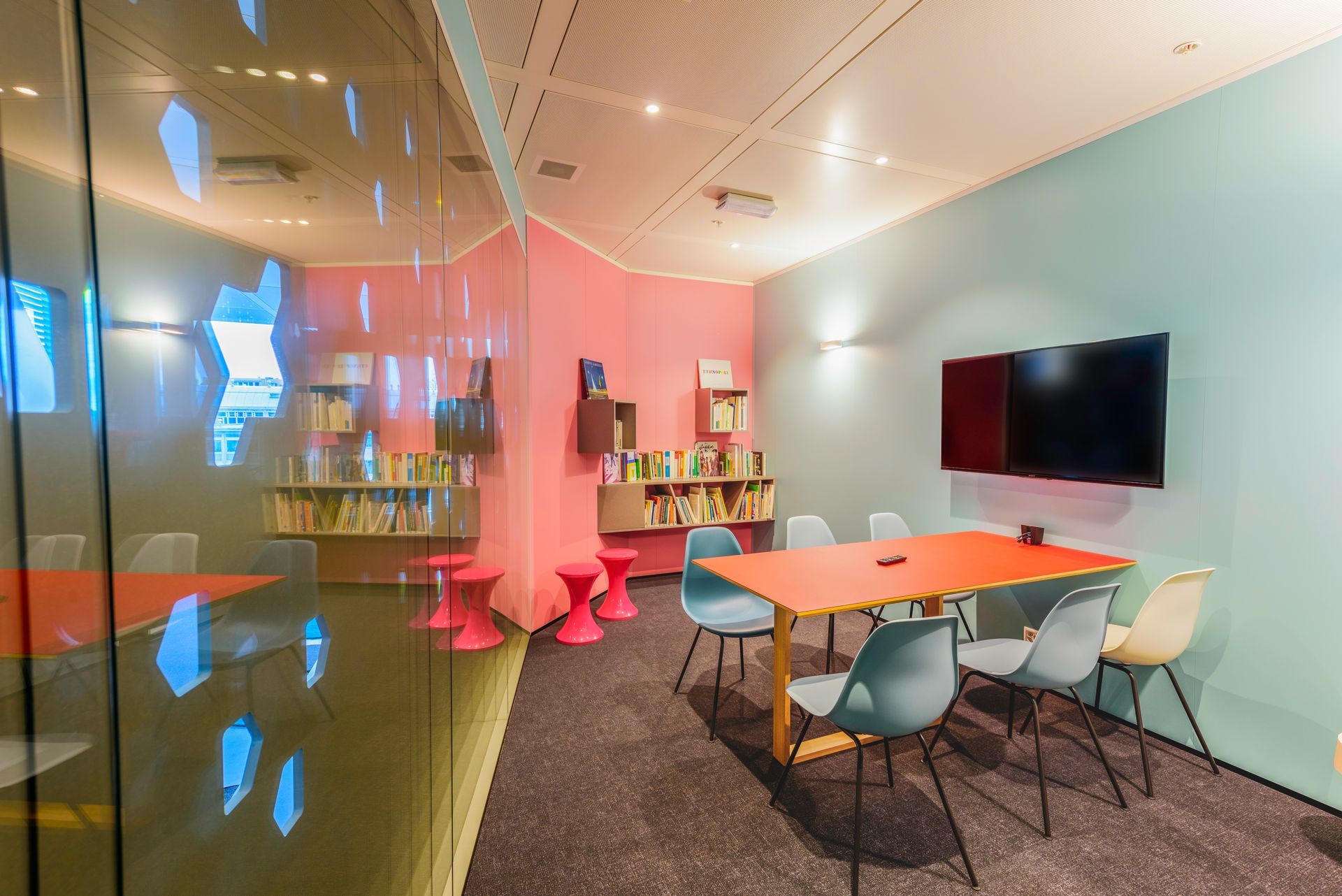 A room with a table and chairs and a television on the wall.