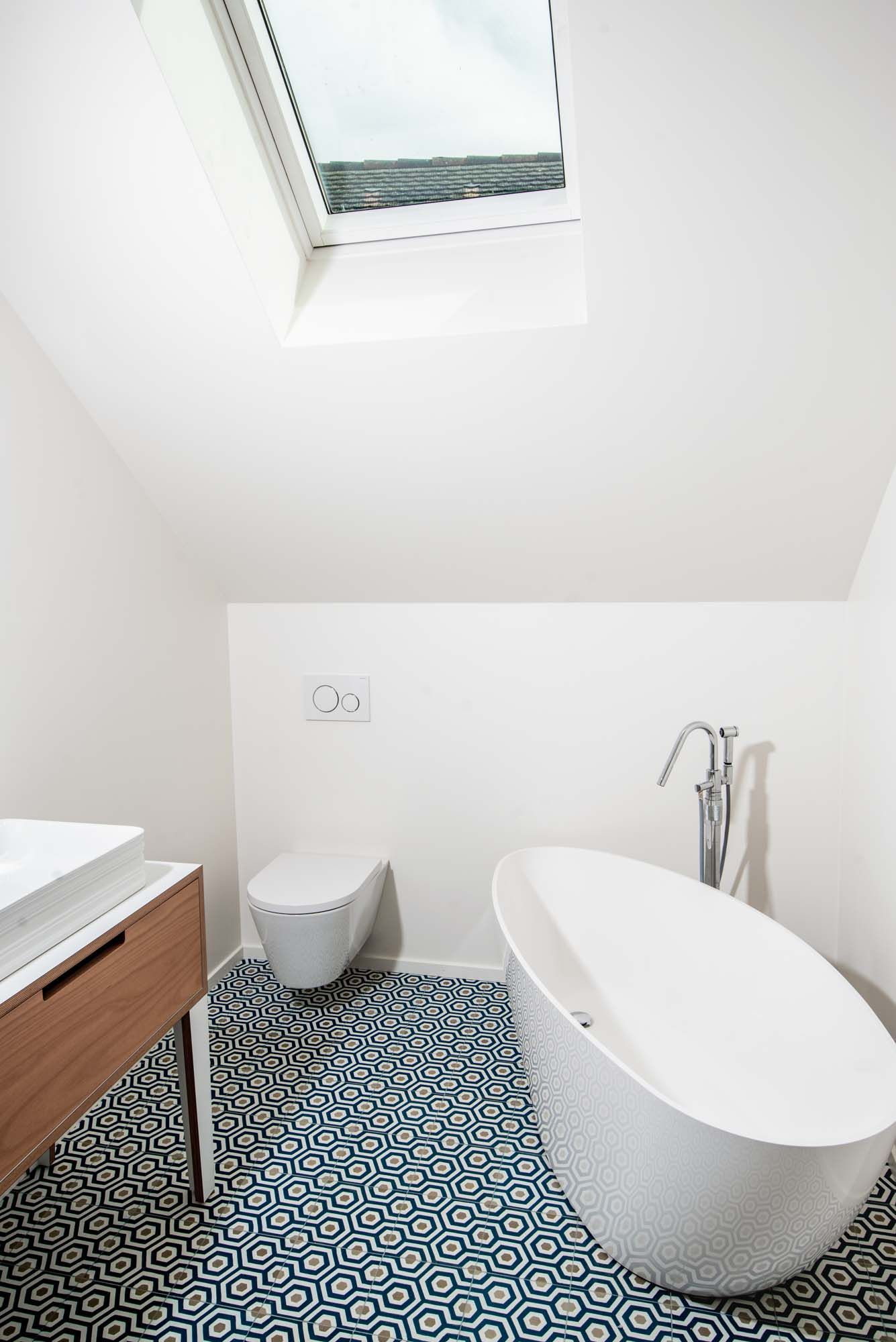A bathroom with a bathtub , toilet , sink and skylight.