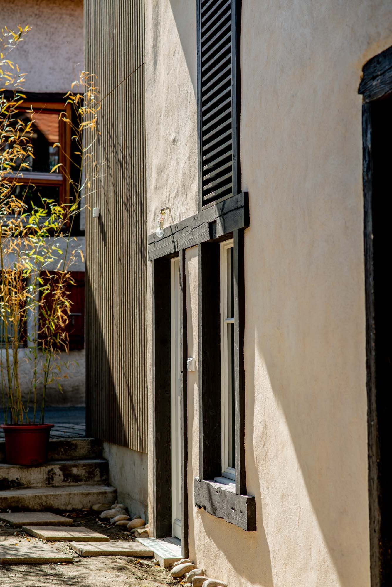 A building with a window and shutters on the side of it.