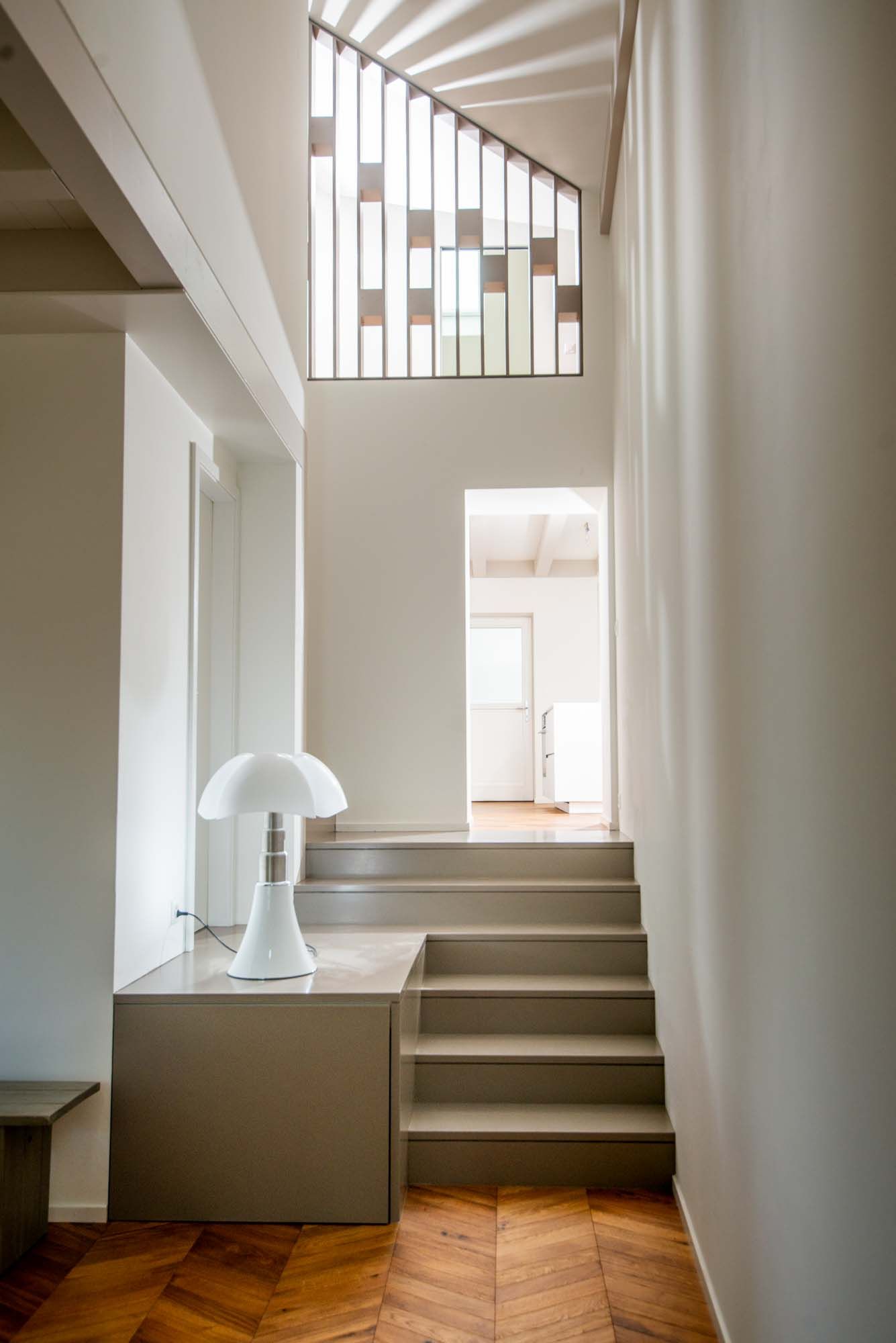 A hallway with stairs and a lamp on the floor.
