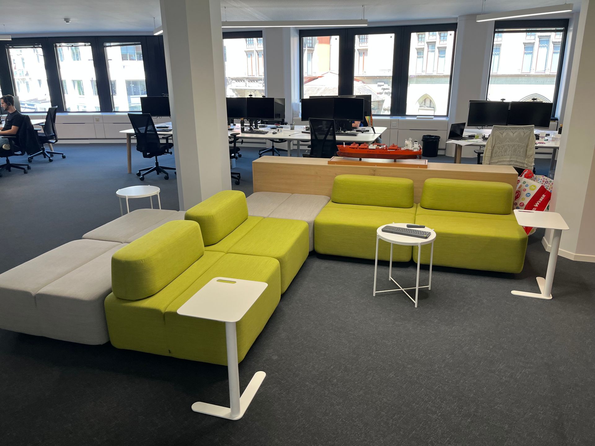 An office with a green couch and white tables