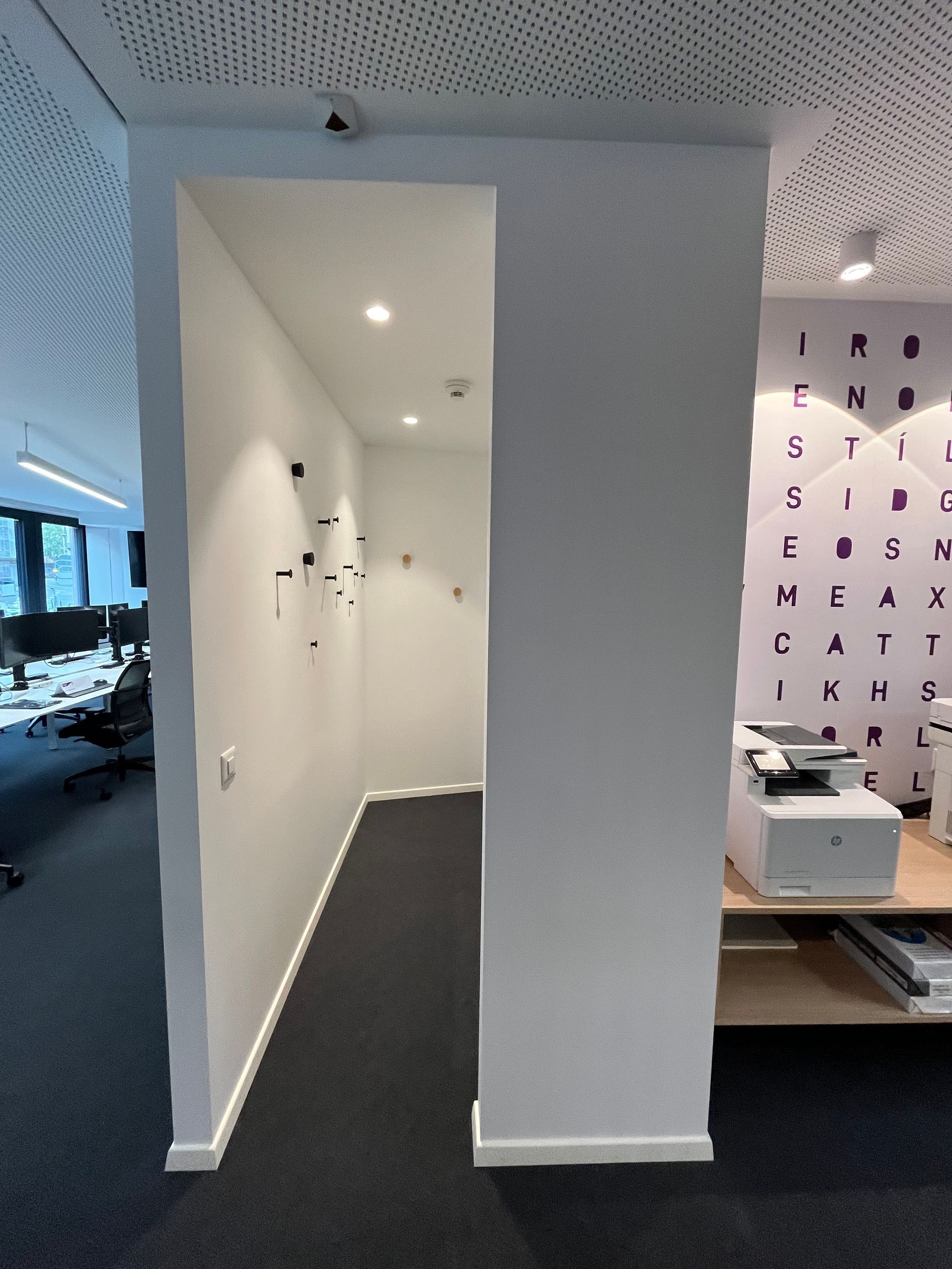 A hallway in an office with a printer on a desk