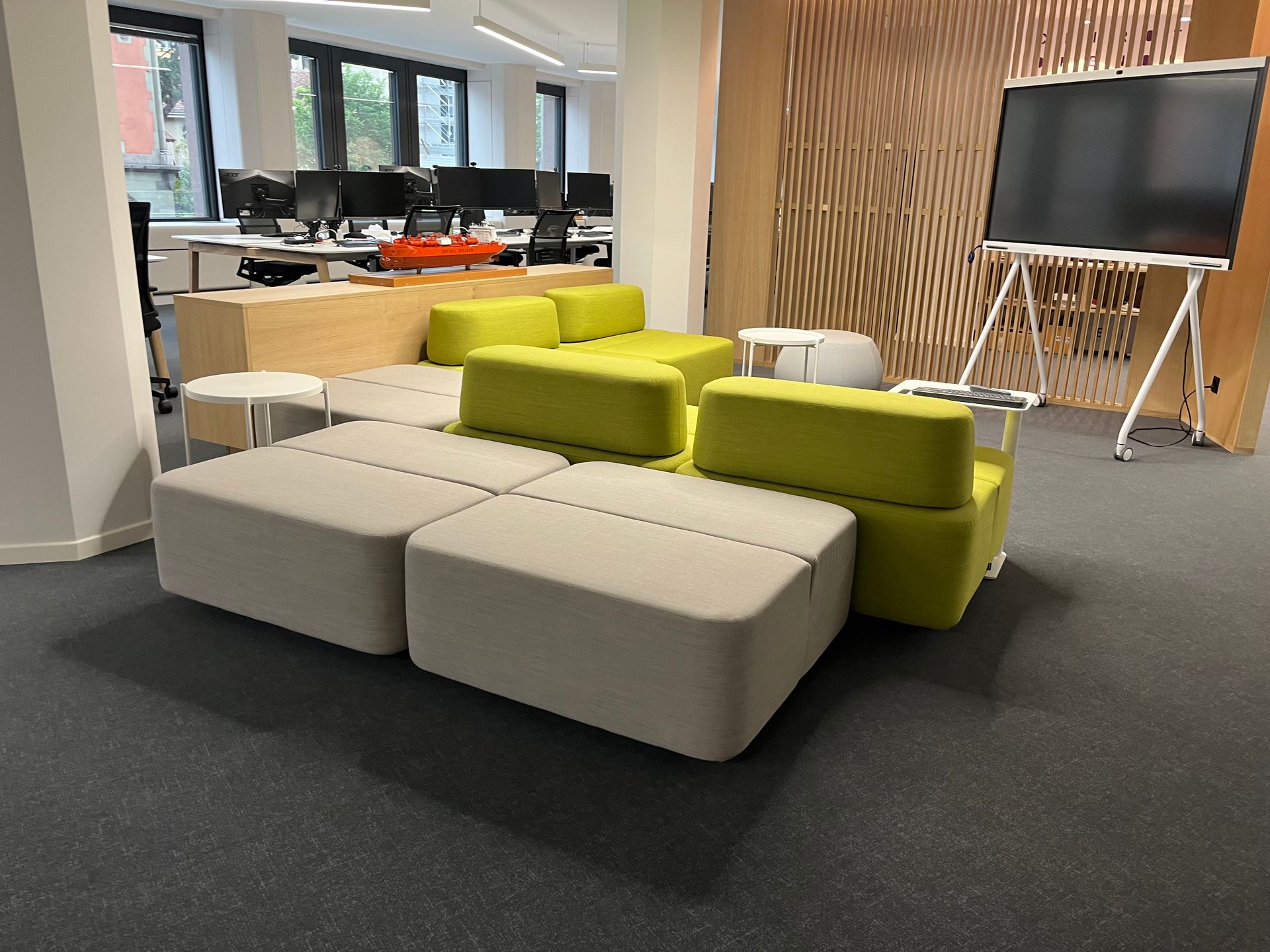 A living room with green chairs and ottomans in an office
