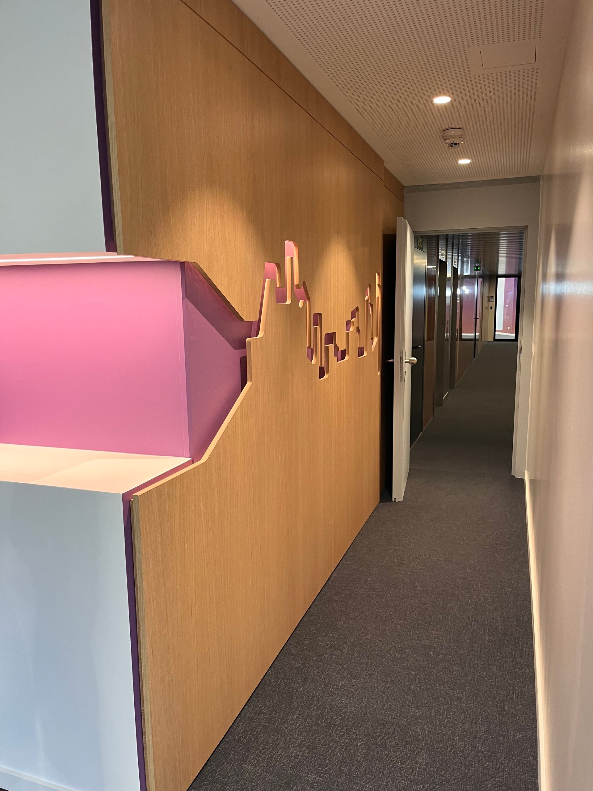 A hallway with a wooden wall and a pink sculpture on the wall