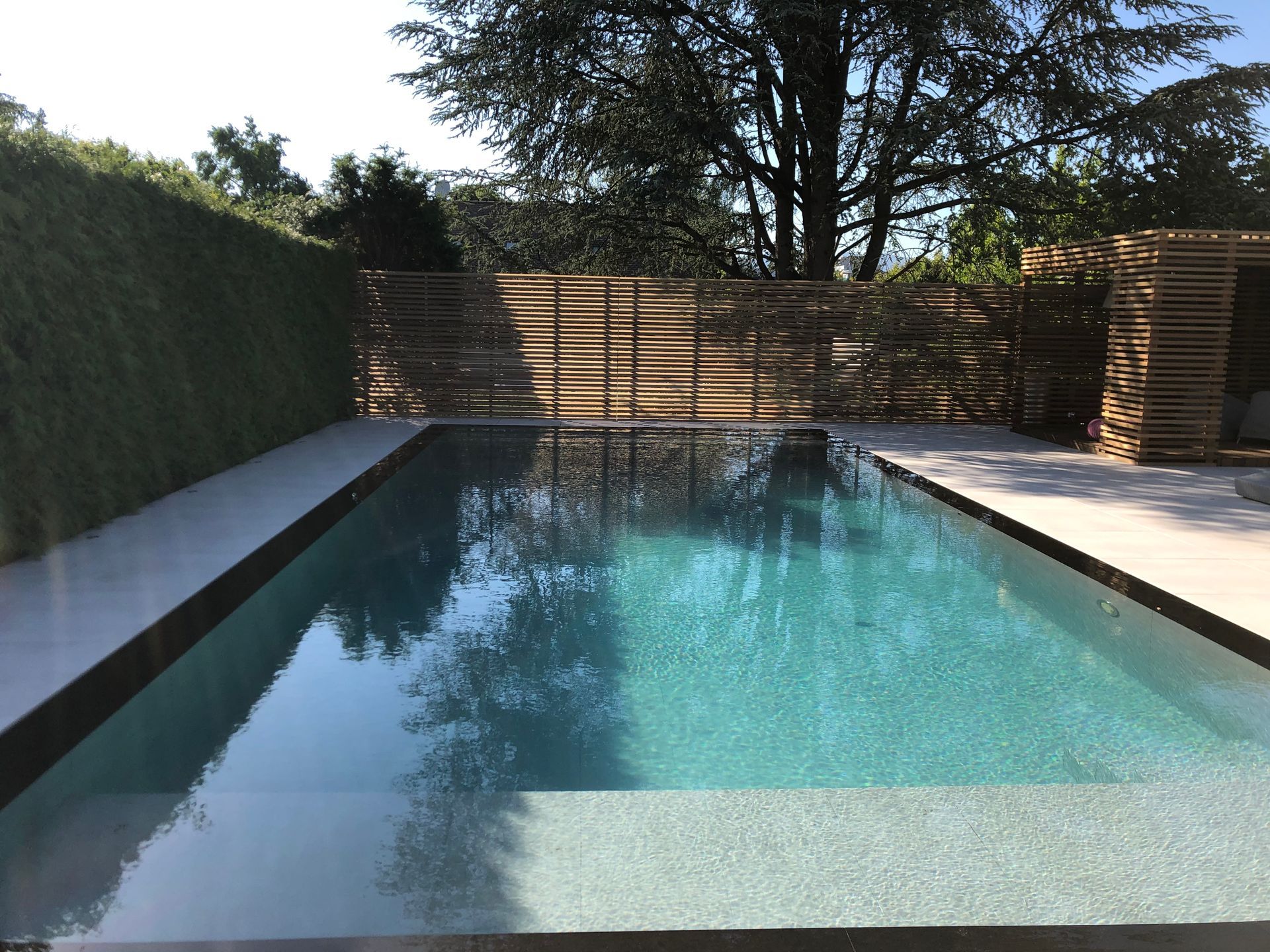 A large swimming pool surrounded by trees and a fence