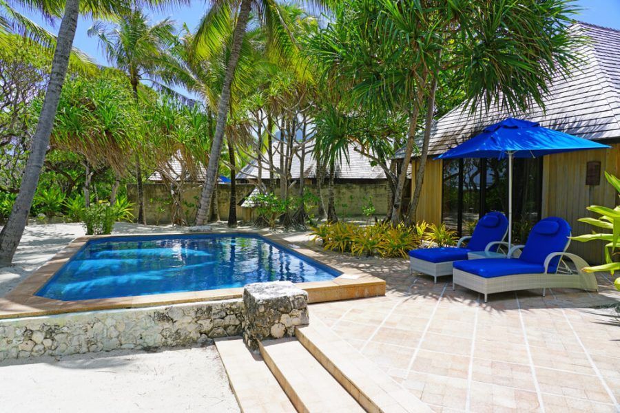 Espace détente au bord de la piscine avec piscine, chaises bleues et parasol bleu.