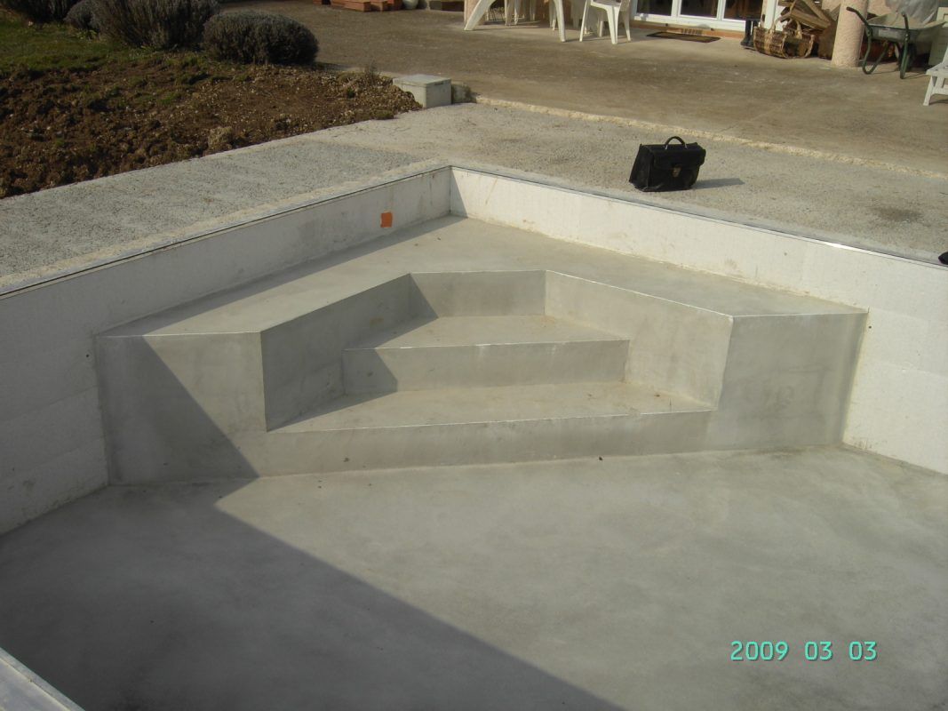 Escaliers de piscine en béton en construction. Des marches en béton gris mènent à un bassin de piscine rectangulaire.