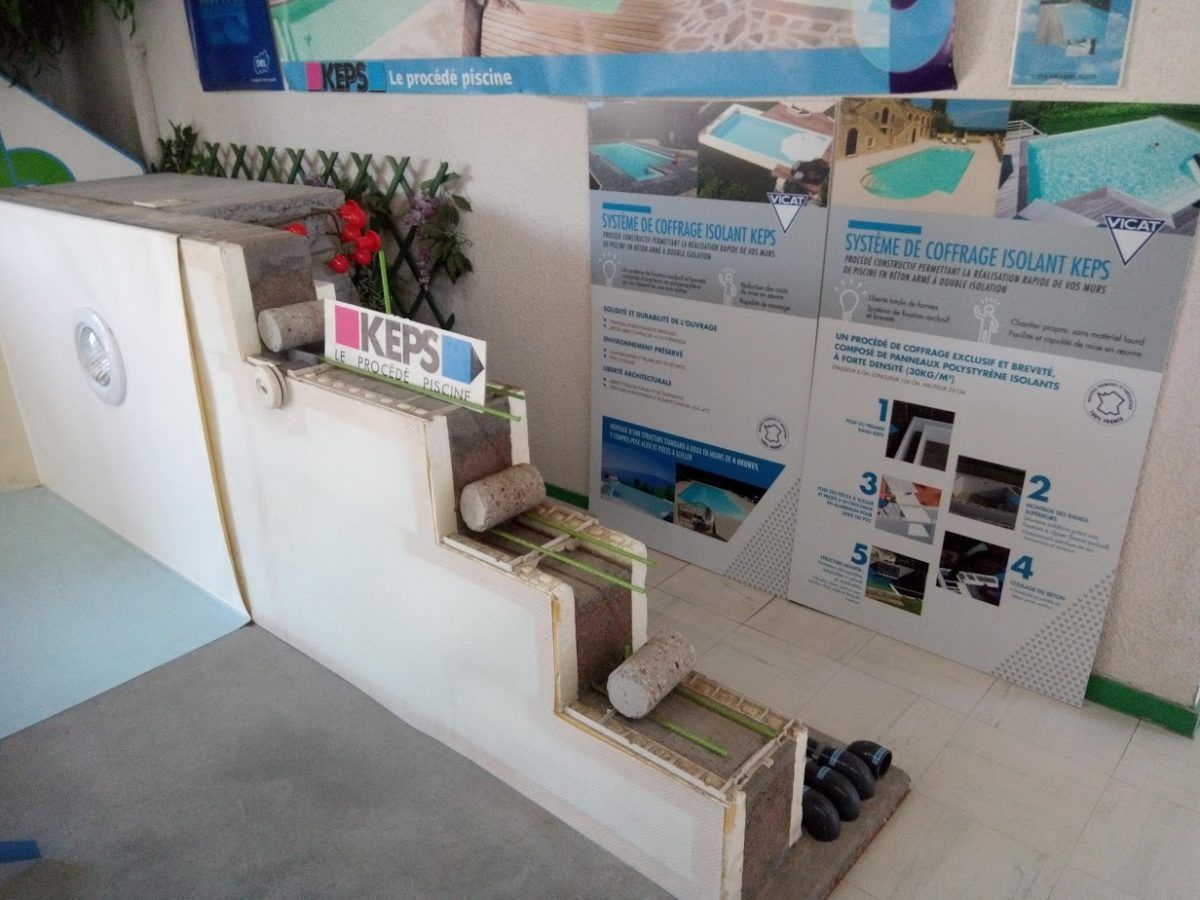 Maquette de construction de piscine avec escaliers, affiches informatives et composition florale décorative.