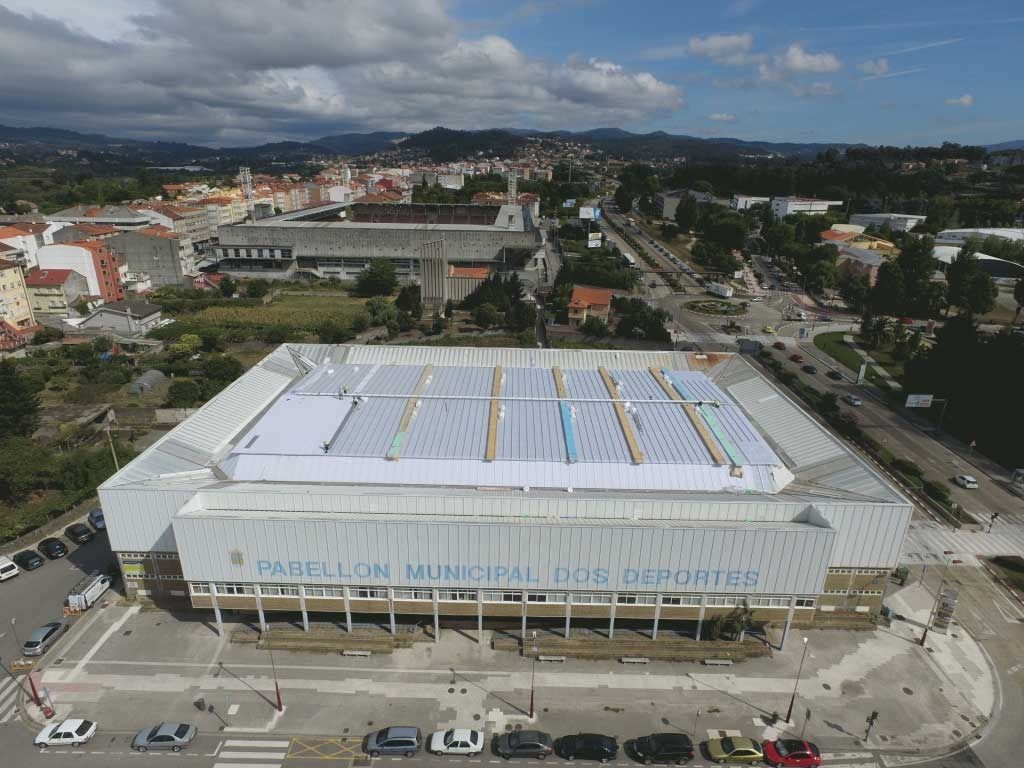 Vista aérea de un gran edificio municipal blanco con un área de estacionamiento en la azotea en una ciudad.