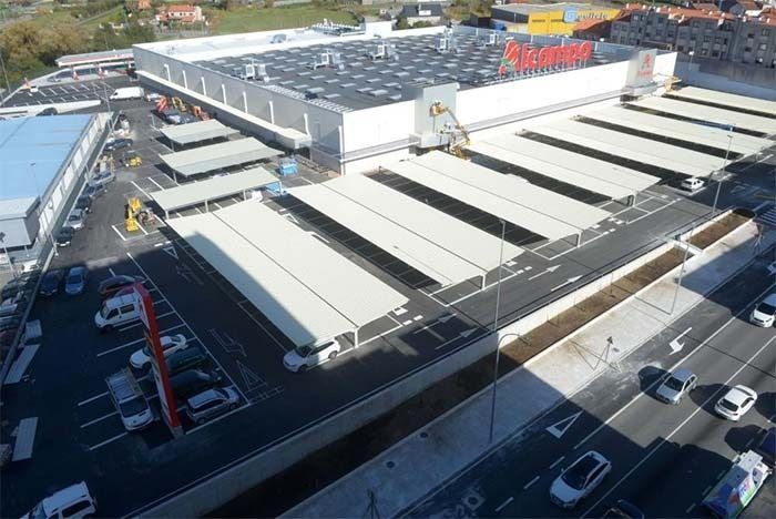 Vista aérea de una gran tienda con toldos blancos y un aparcamiento debajo.