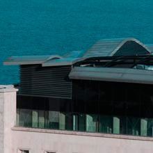 Edificio moderno con techo de cristal junto a aguas turquesas.