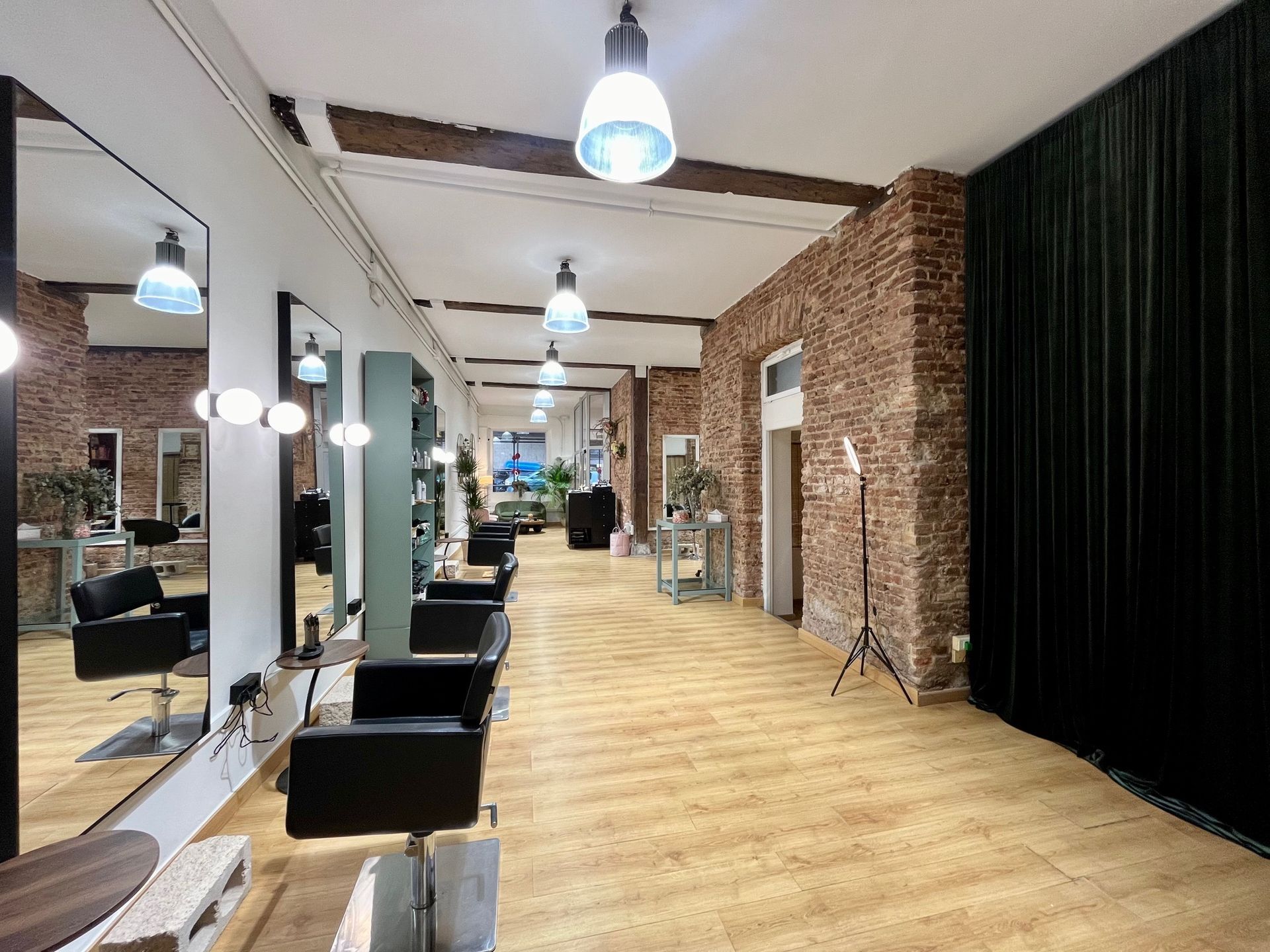 Un largo pasillo en una peluquería con sillas y espejos.