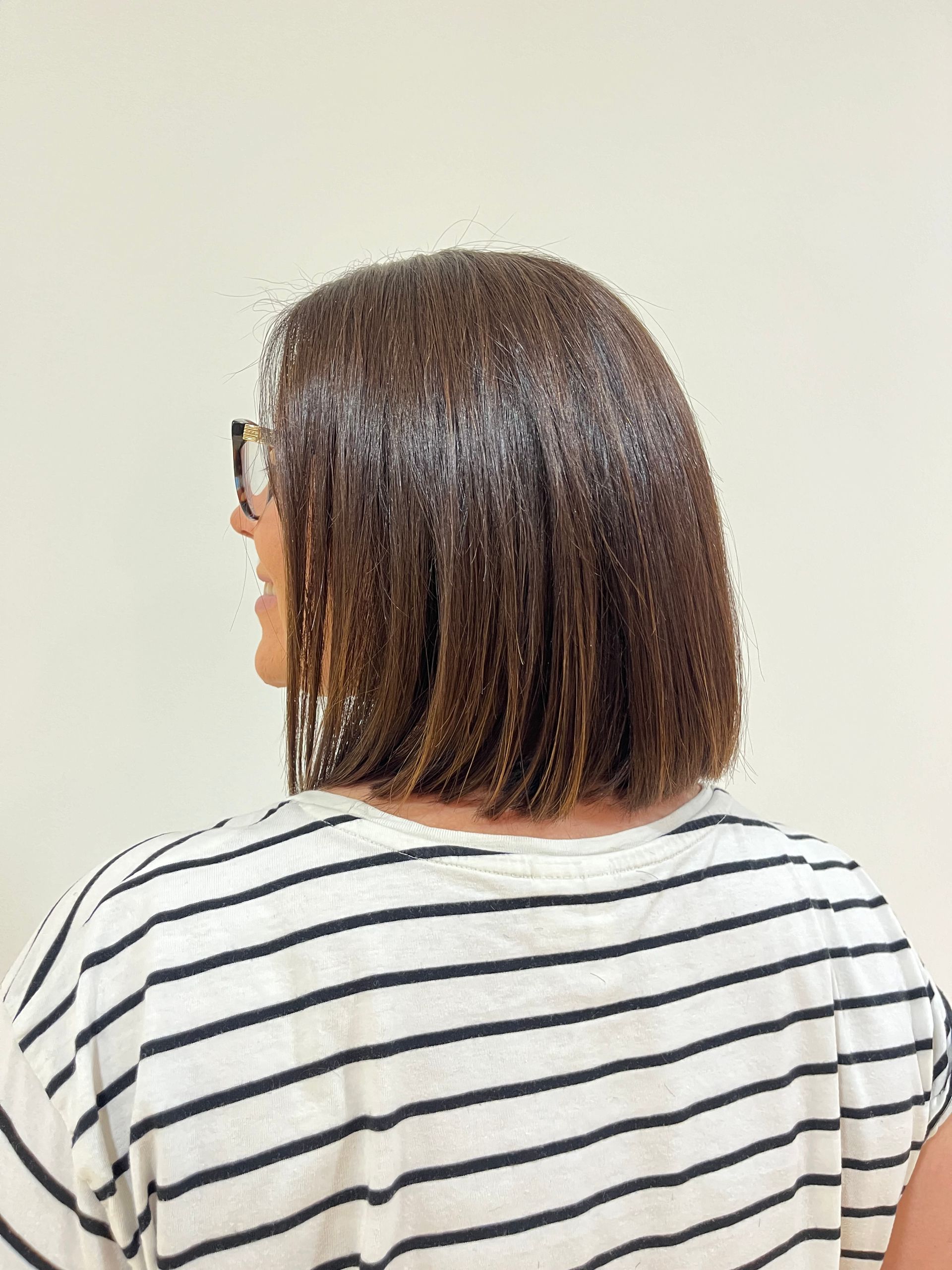 La espalda de una mujer con gafas y una camisa de rayas.