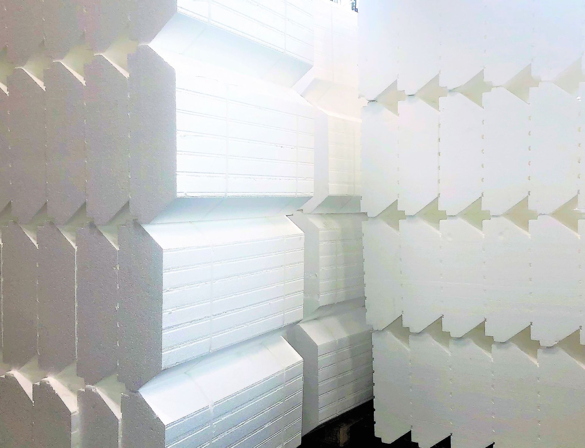 Pilas de paneles aislantes de espuma blanca con bordes entrelazados.