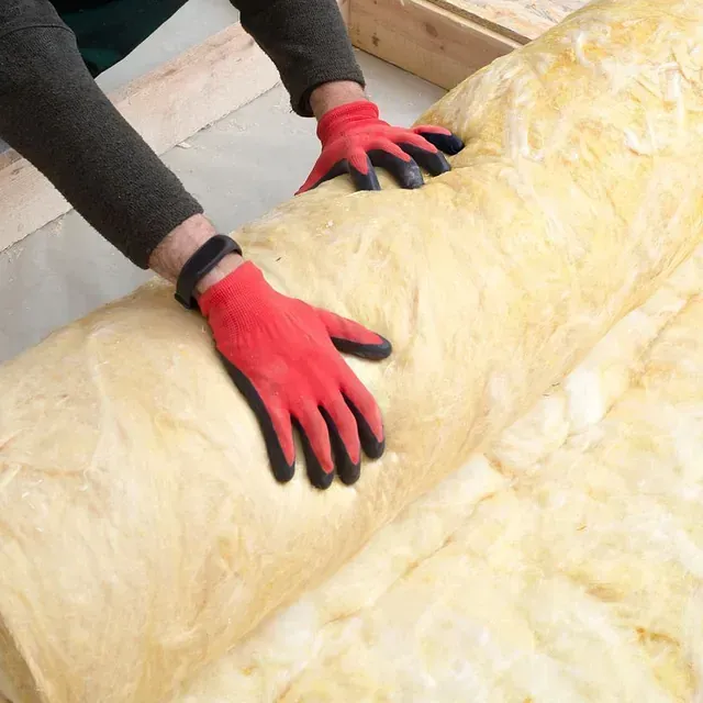 Persona que lleva guantes rojos desenrollando el aislamiento en una habitación.