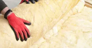 Manos con guantes rojos desenrollando el aislamiento.