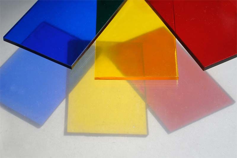 Láminas transparentes de colores: azul, amarillo, naranja, rojo y verde, superpuestas, sobre una superficie blanca.