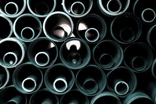 Disposición en mosaico de tubos de color gris oscuro, de tamaño variable, creando un patrón de círculos concéntricos.