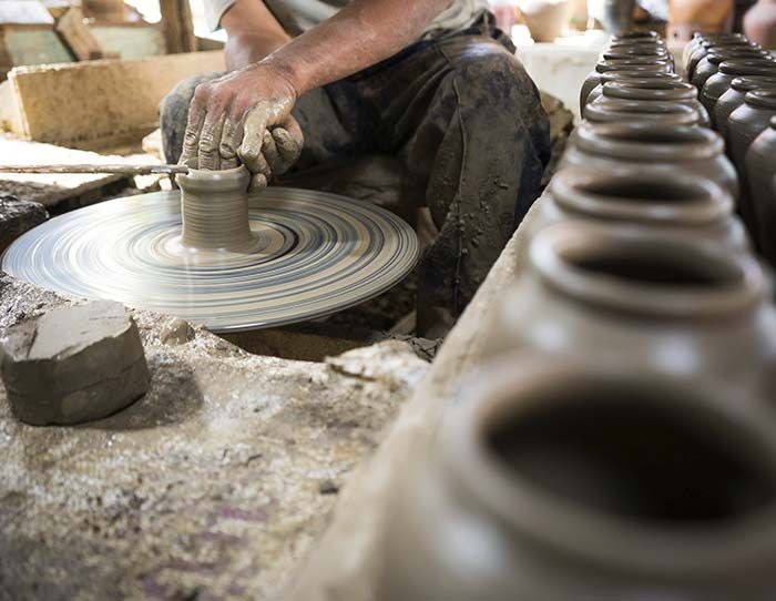 Alfarero dando forma a la arcilla en un torno giratorio, creando cerámica en un taller.