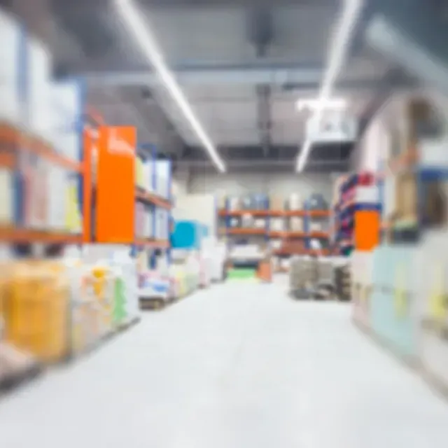 Vista borrosa de un pasillo de almacén con estantes de productos e iluminación superior.