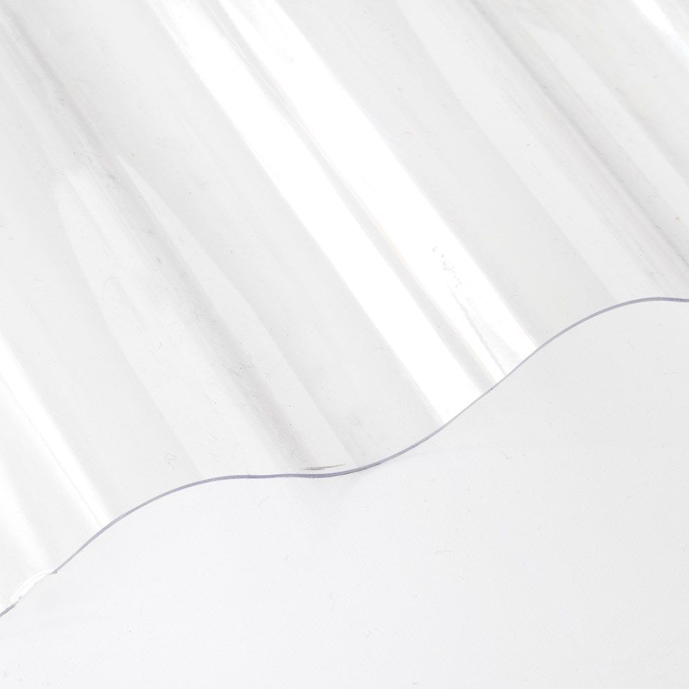 Material de techado corrugado transparente sobre una superficie blanca.