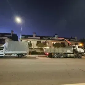 Dos camiones están estacionados al costado de la carretera por la noche.