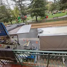 Un balcón con vista a un parque y un camión.